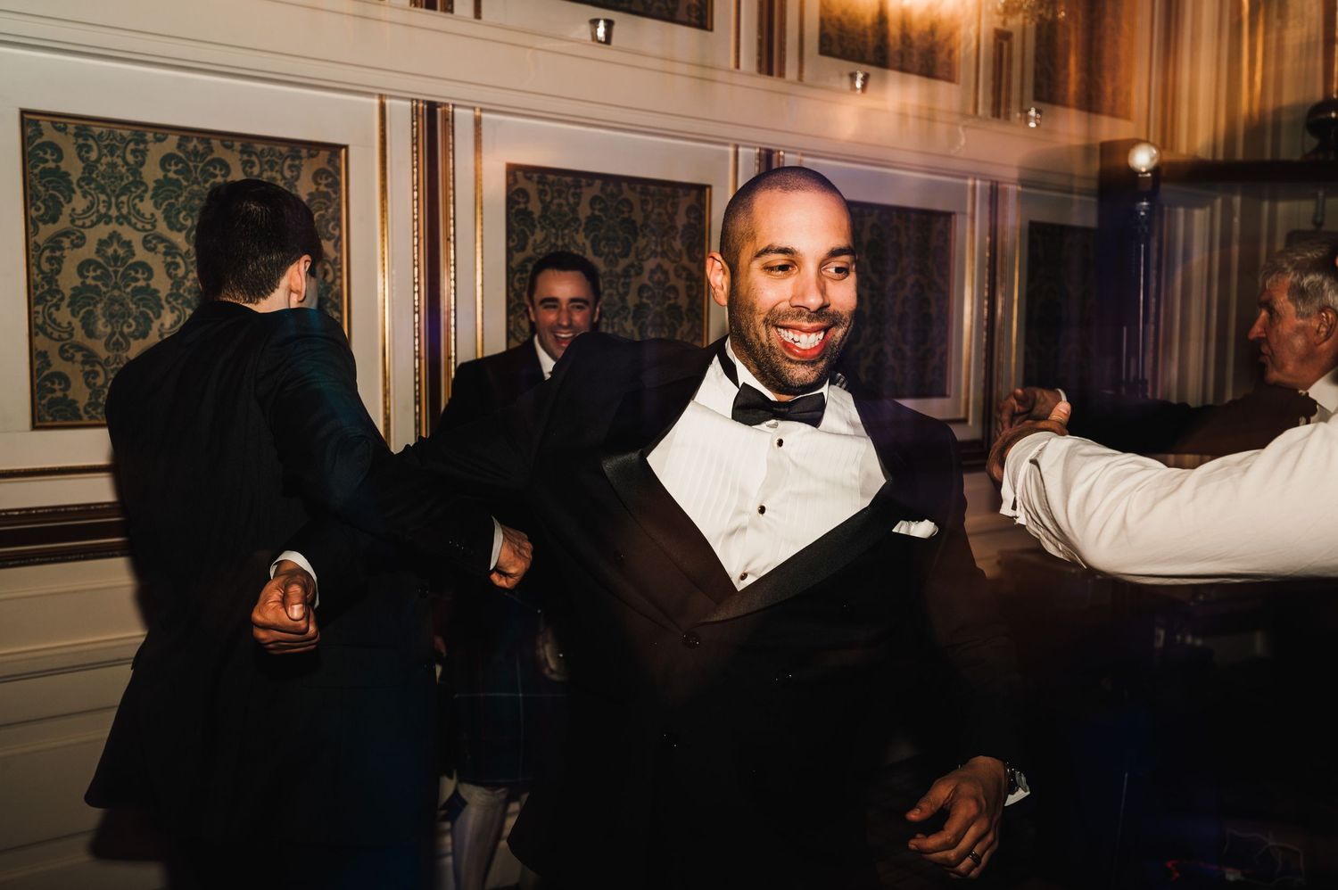 A smiling guest in a tuxedo enjoying the wedding reception festivities.