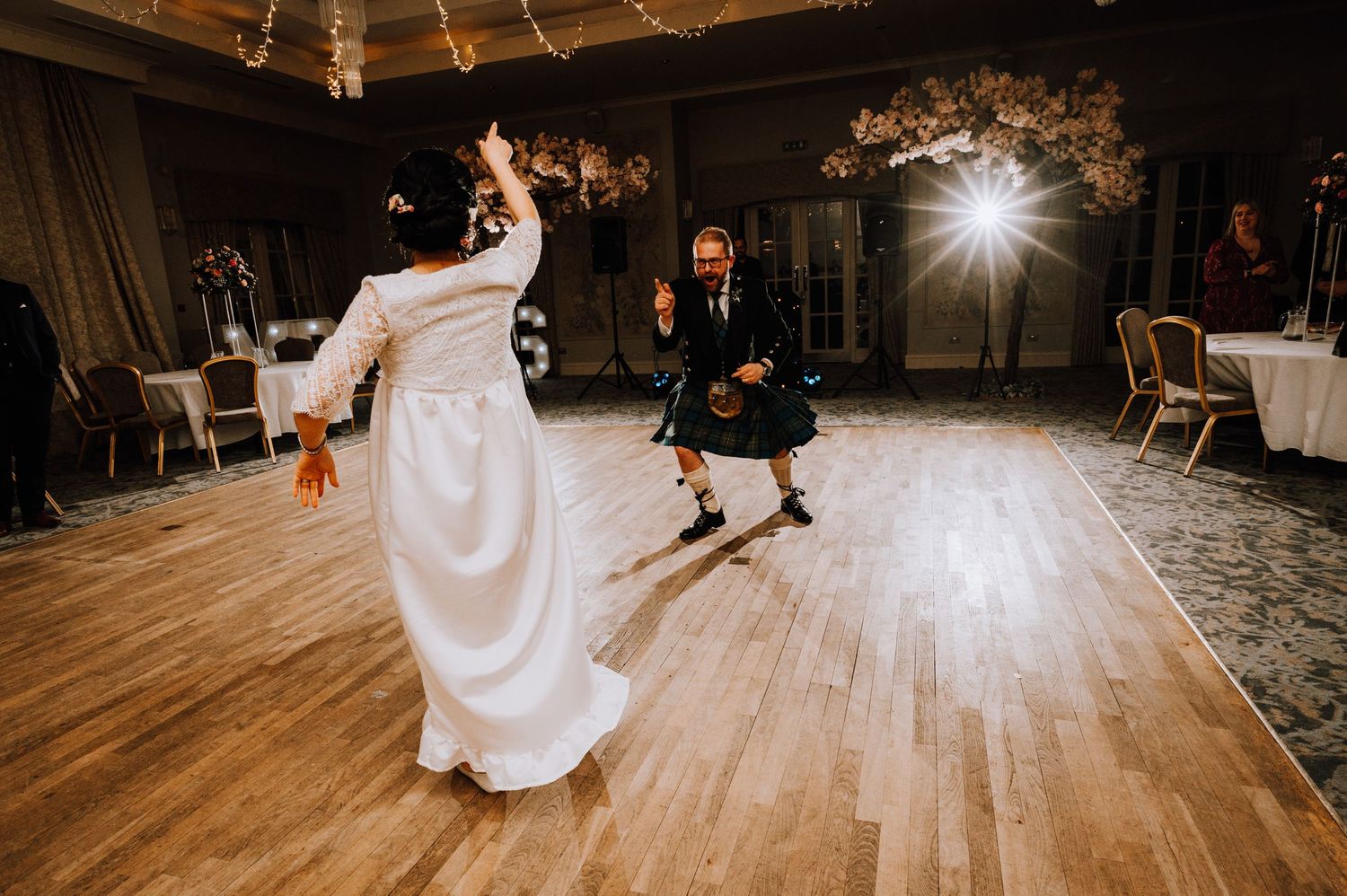 Couple performing energetic cultural fusion dance at wedding reception.