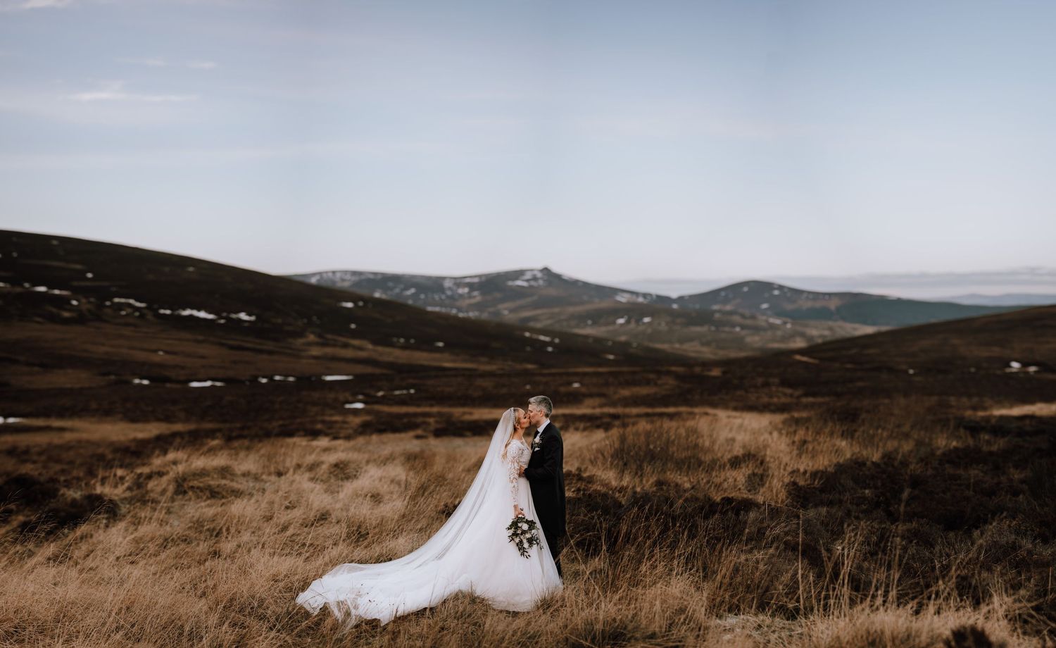 Elegant wedding portrait set against expansive mountain scenery and autumn colors.