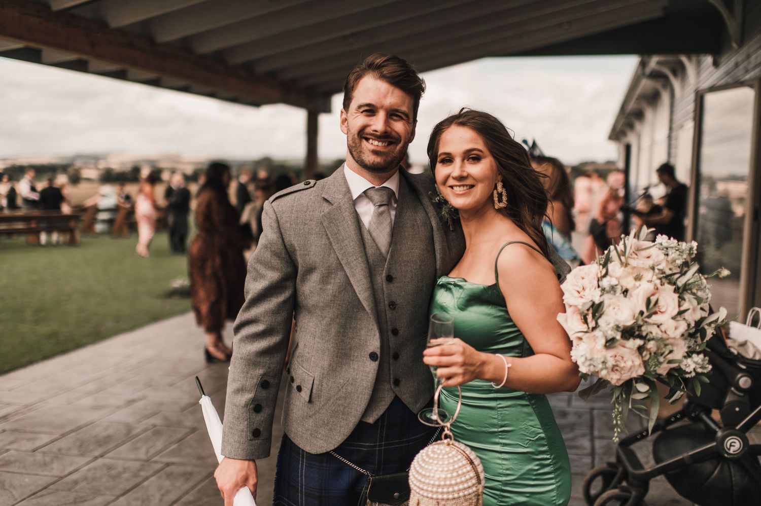A couple poses at an outdoor wedding reception venue with decorative floral arrangements.
