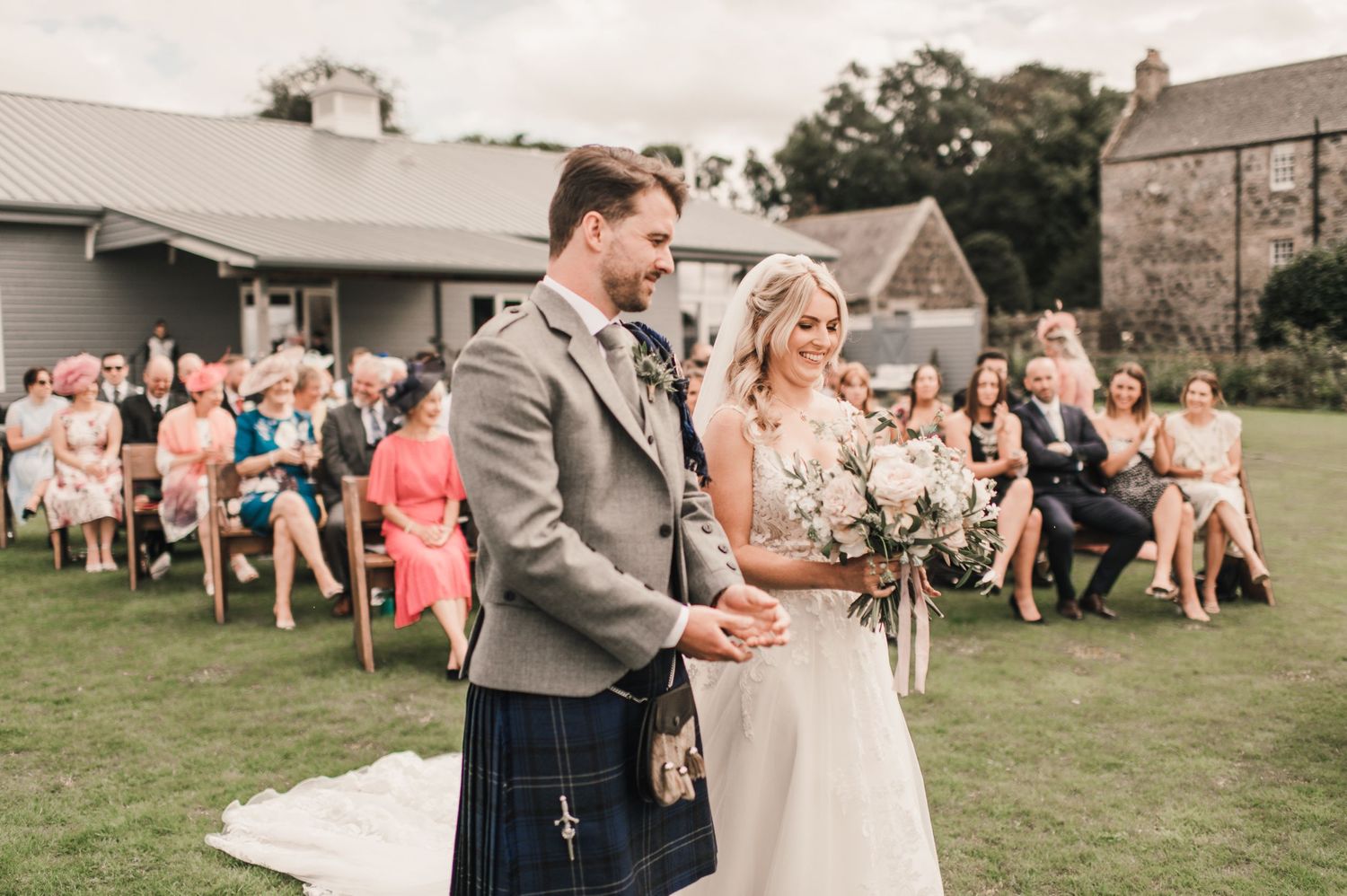 A wedding ceremony on a lawn with guests seated and the couple standing at the front.