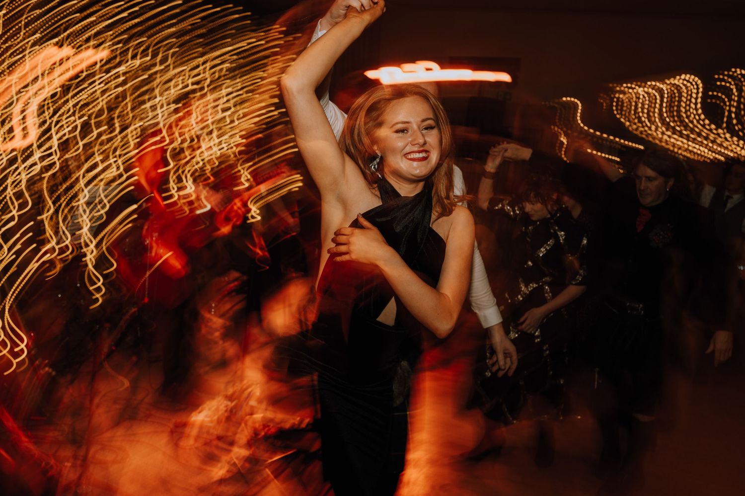 A guest dances energetically under dramatic lighting at an evening celebration.
