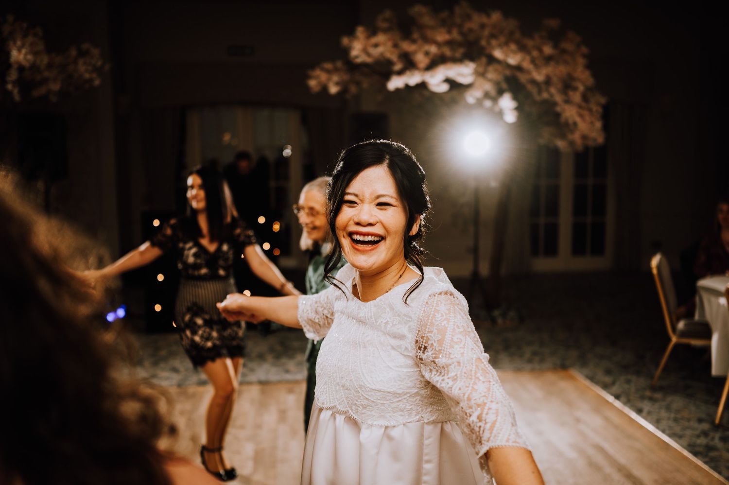 Person dancing joyfully at an evening celebration with warm lighting and decorative elements.