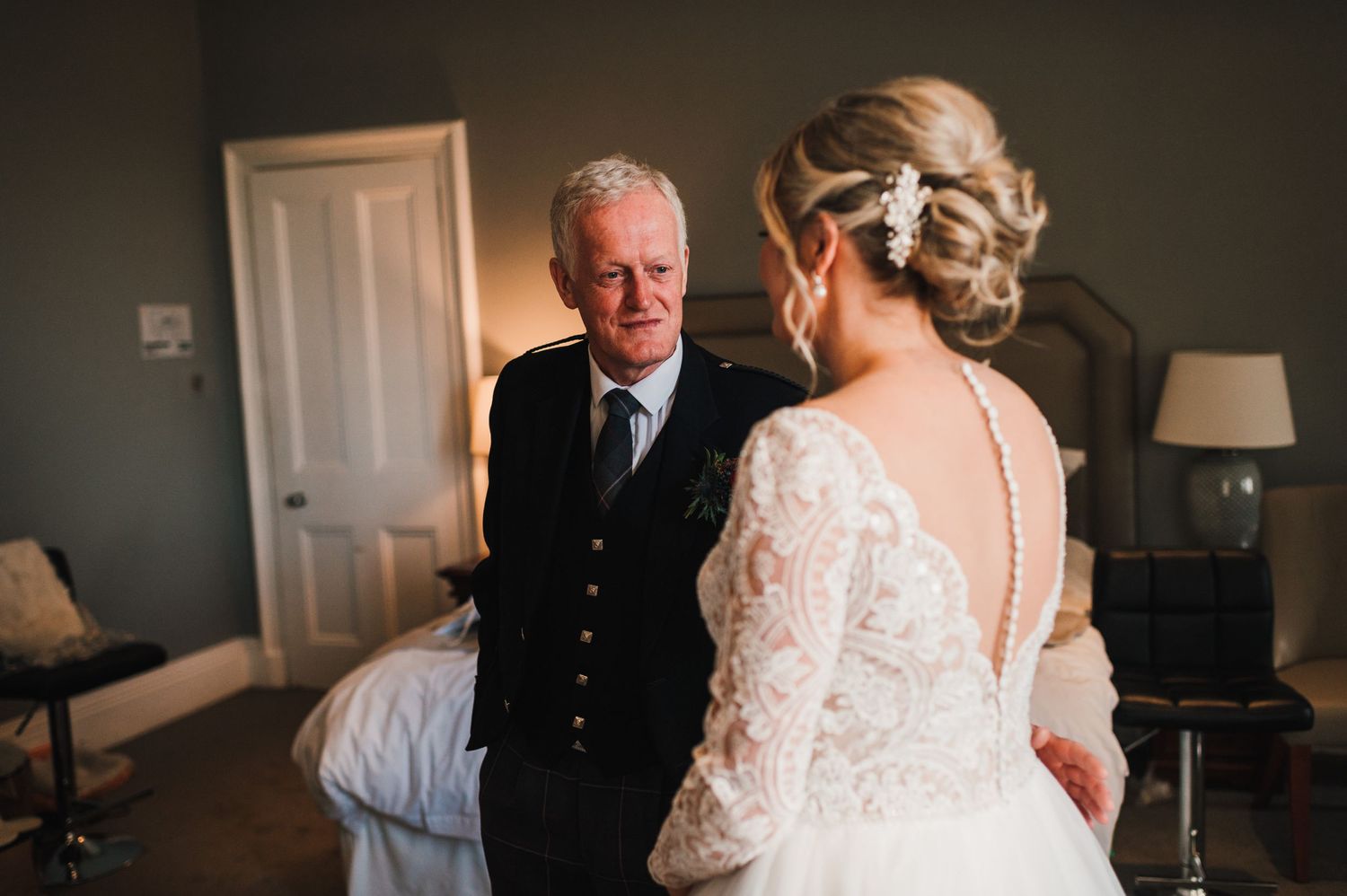 A tender moment captured during wedding preparations in a dimly lit room.