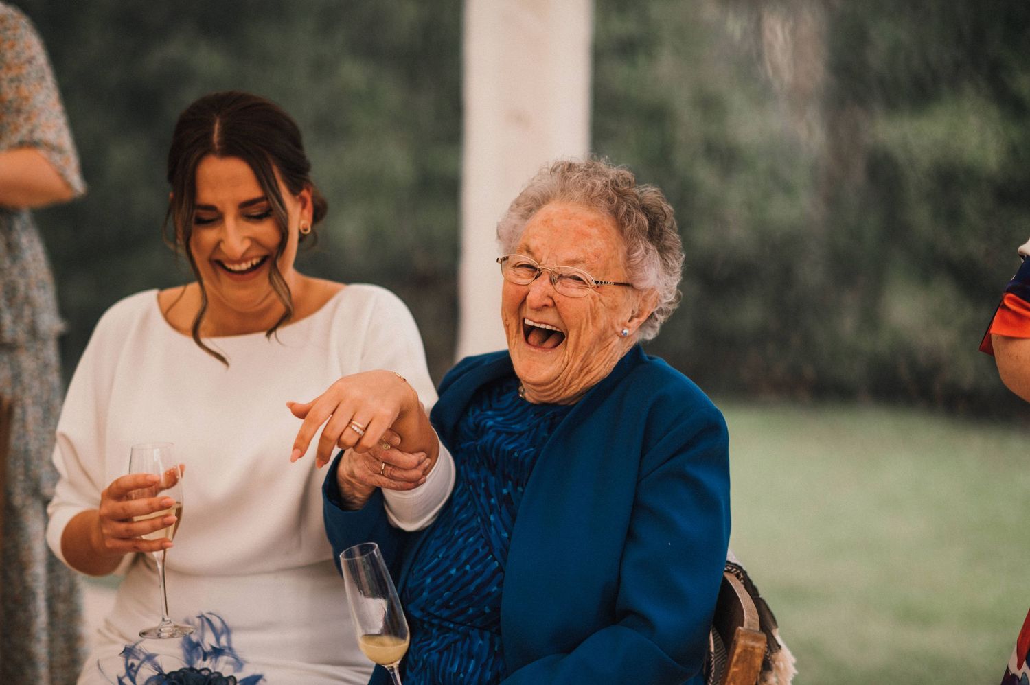 A joyful moment of laughter between two guests at an outdoor celebration.