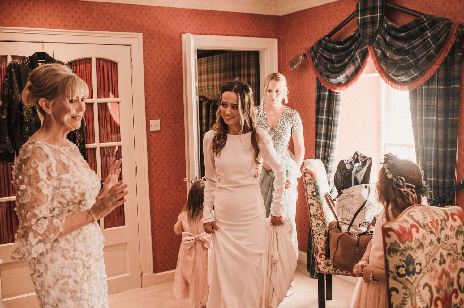 Wedding preparation scene in red-wallpapered room with elegant decor.