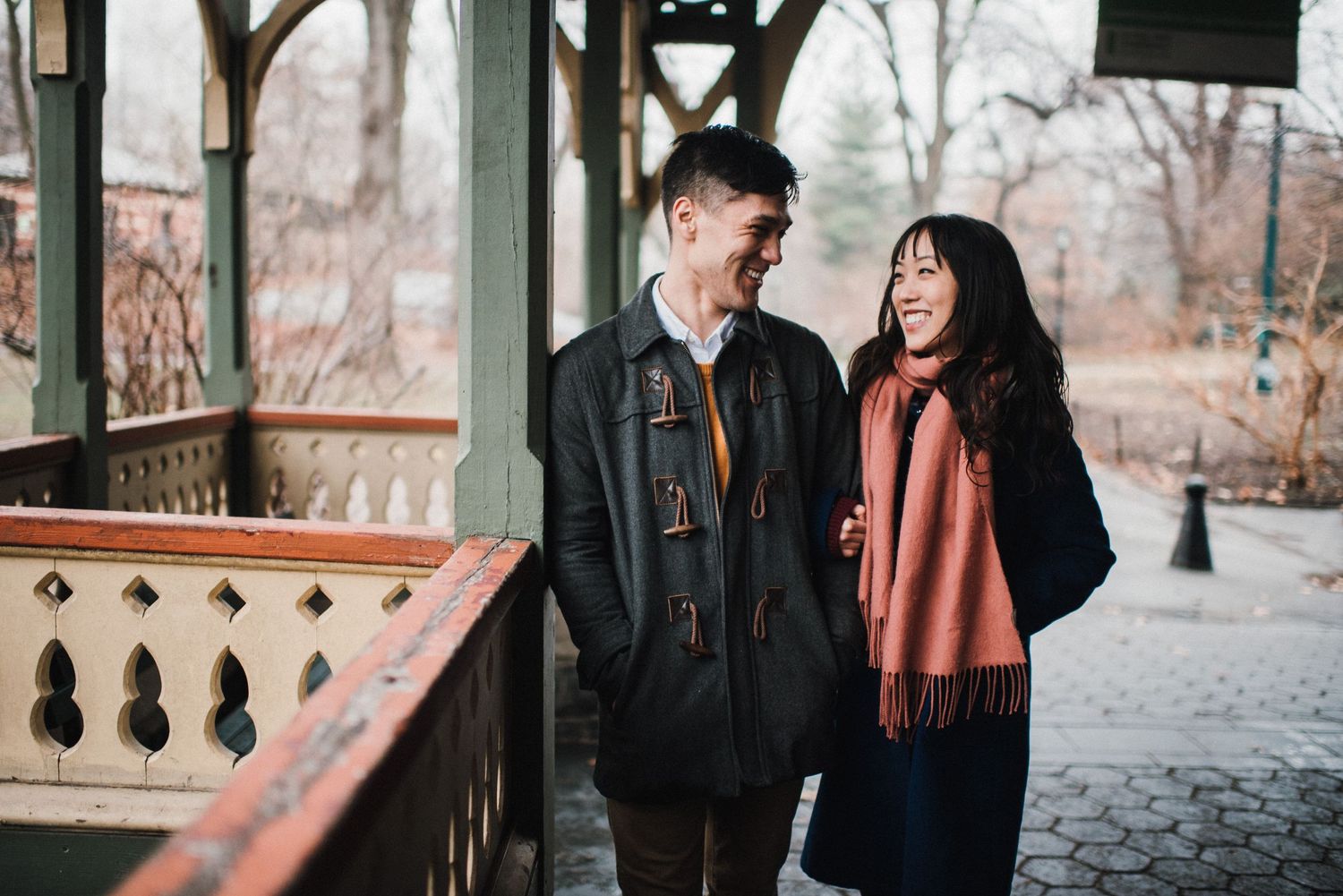 A couple laughs together on a vintage wooden gazebo during autumn.