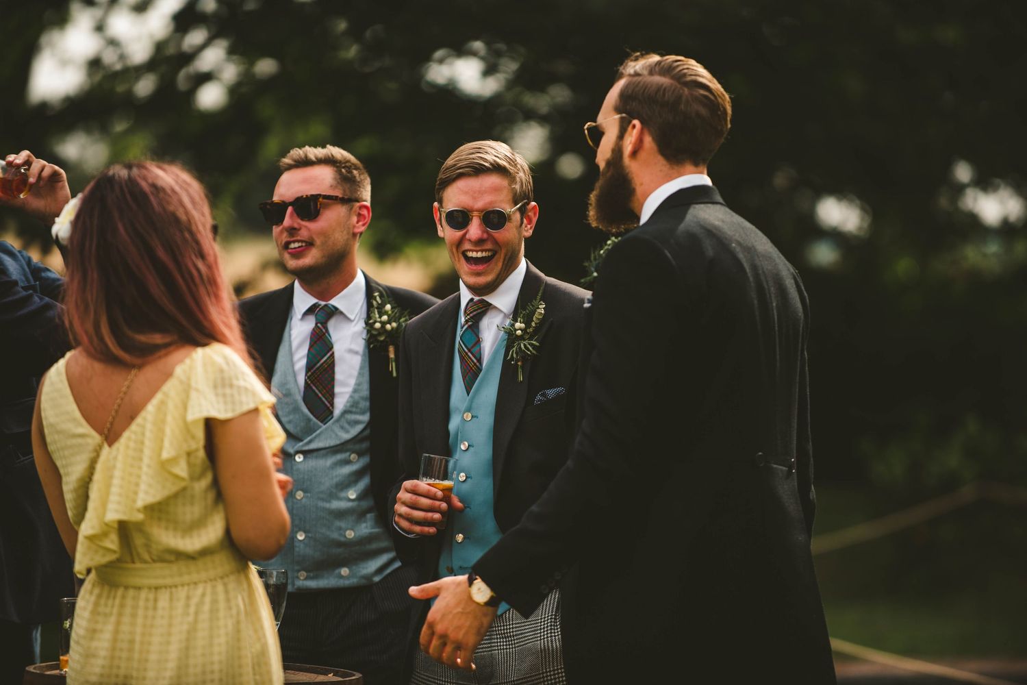Wedding guests in formal attire chatting during outdoor reception.