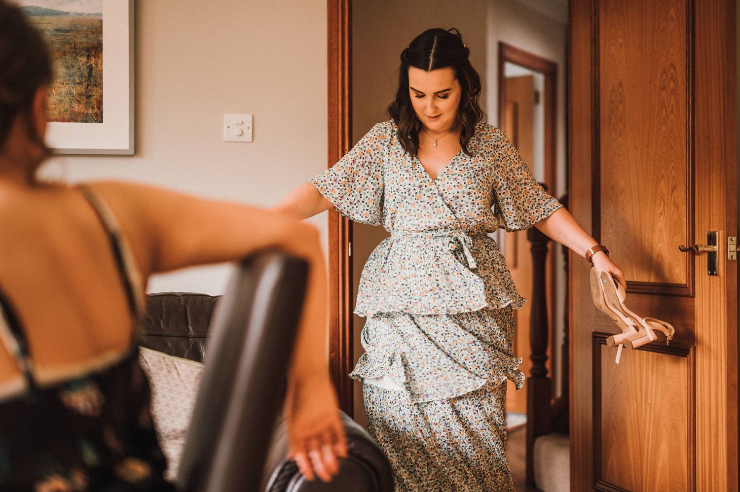 Woman in floral tiered dress preparing for special occasion.