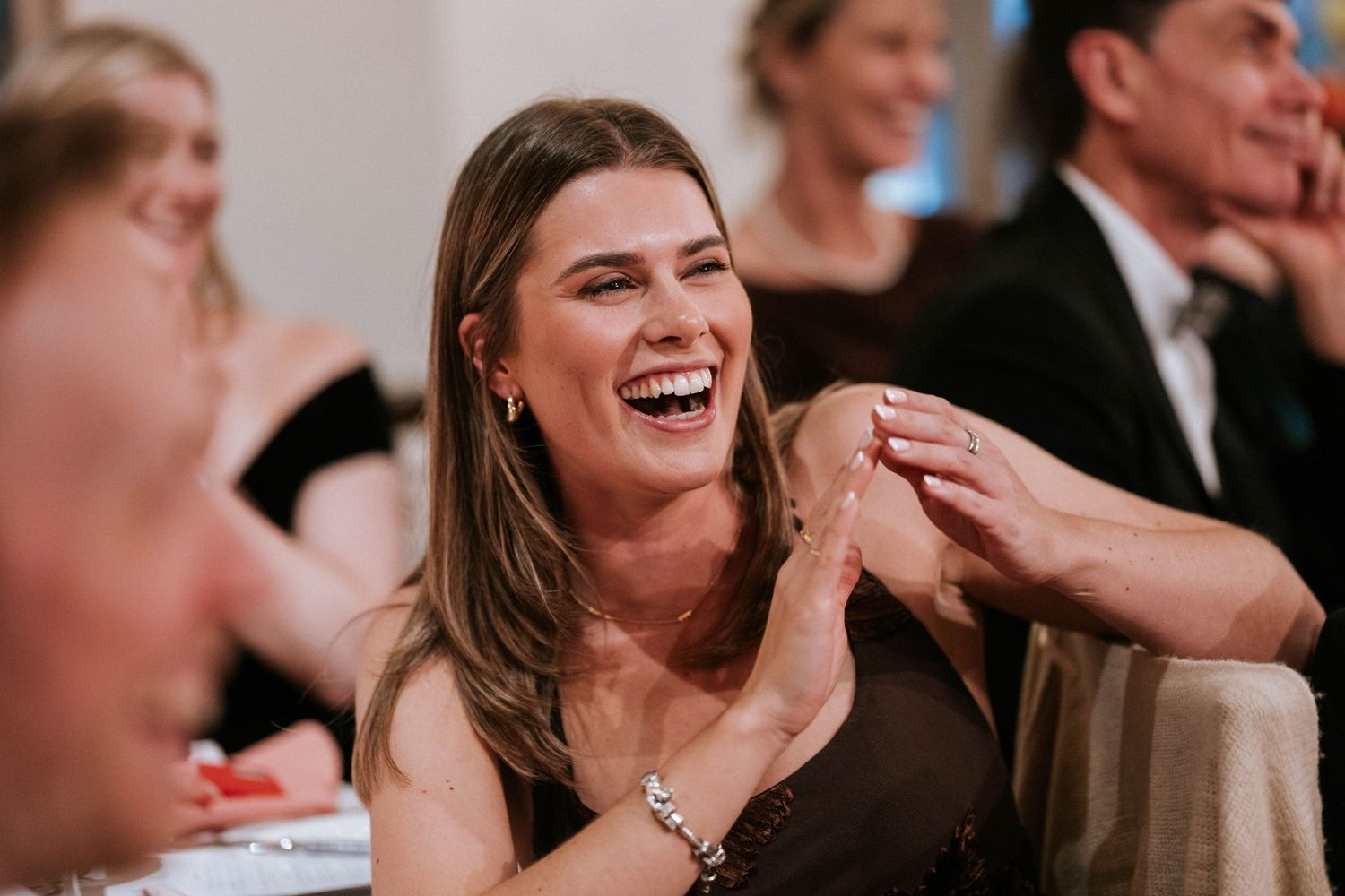 Wedding guests share laughter and smiles during reception speeches.