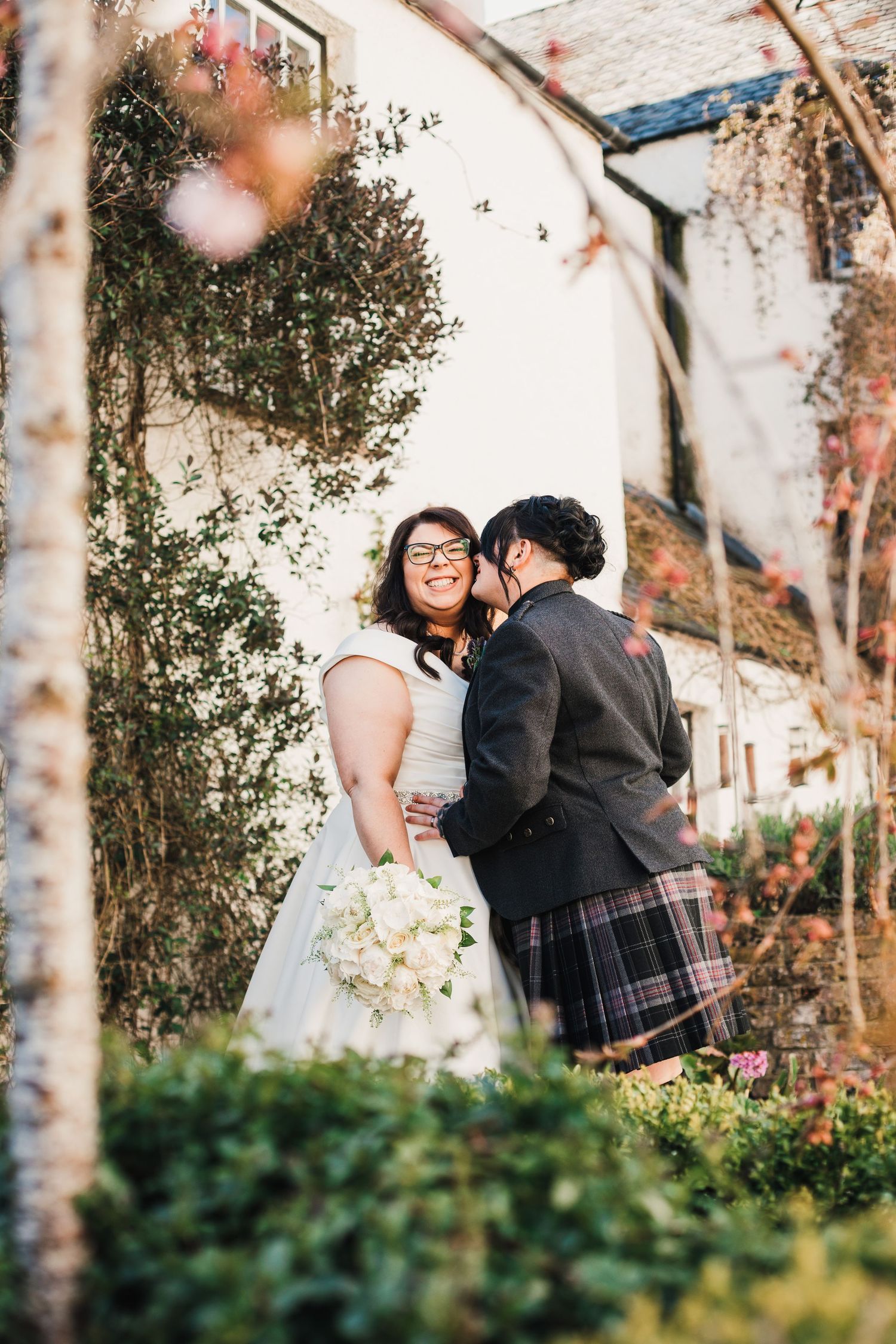 Logie House Wedding Photography. A romantic wedding portrait against a white wall with autumn foliage framing the scene.