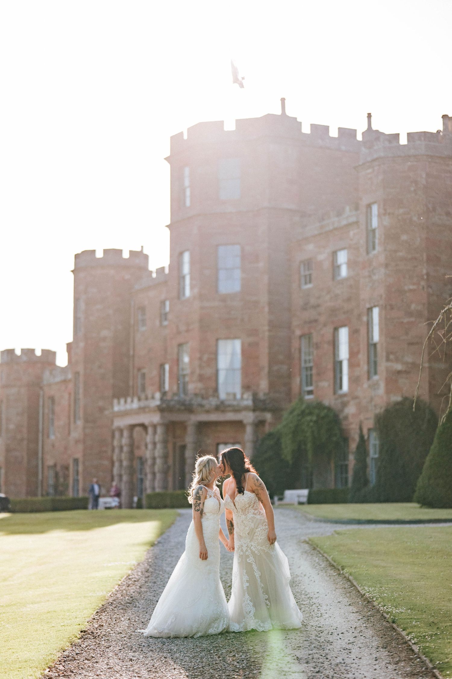 Aberdeen Wedding Photography. Wedding couple poses on path leading to majestic castle during golden hour.