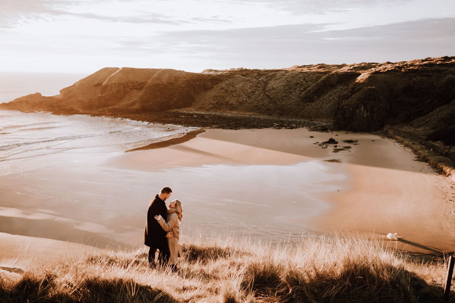 Engagement photography session Aberdeen. A dramatic coastal landscape with cliffs and beach during golden hour.