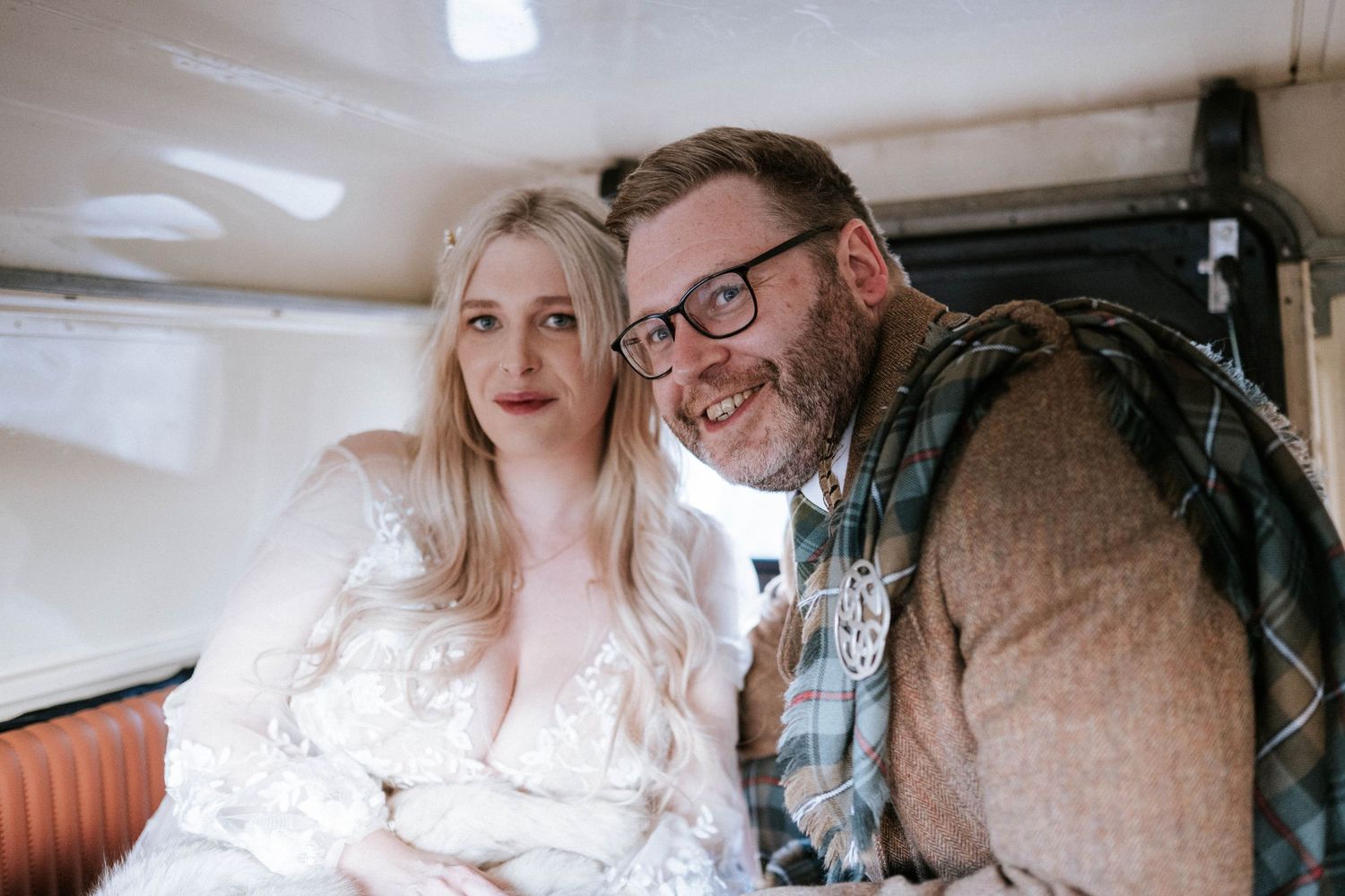 A couple shares a joyful moment together in a vintage vehicle interior.