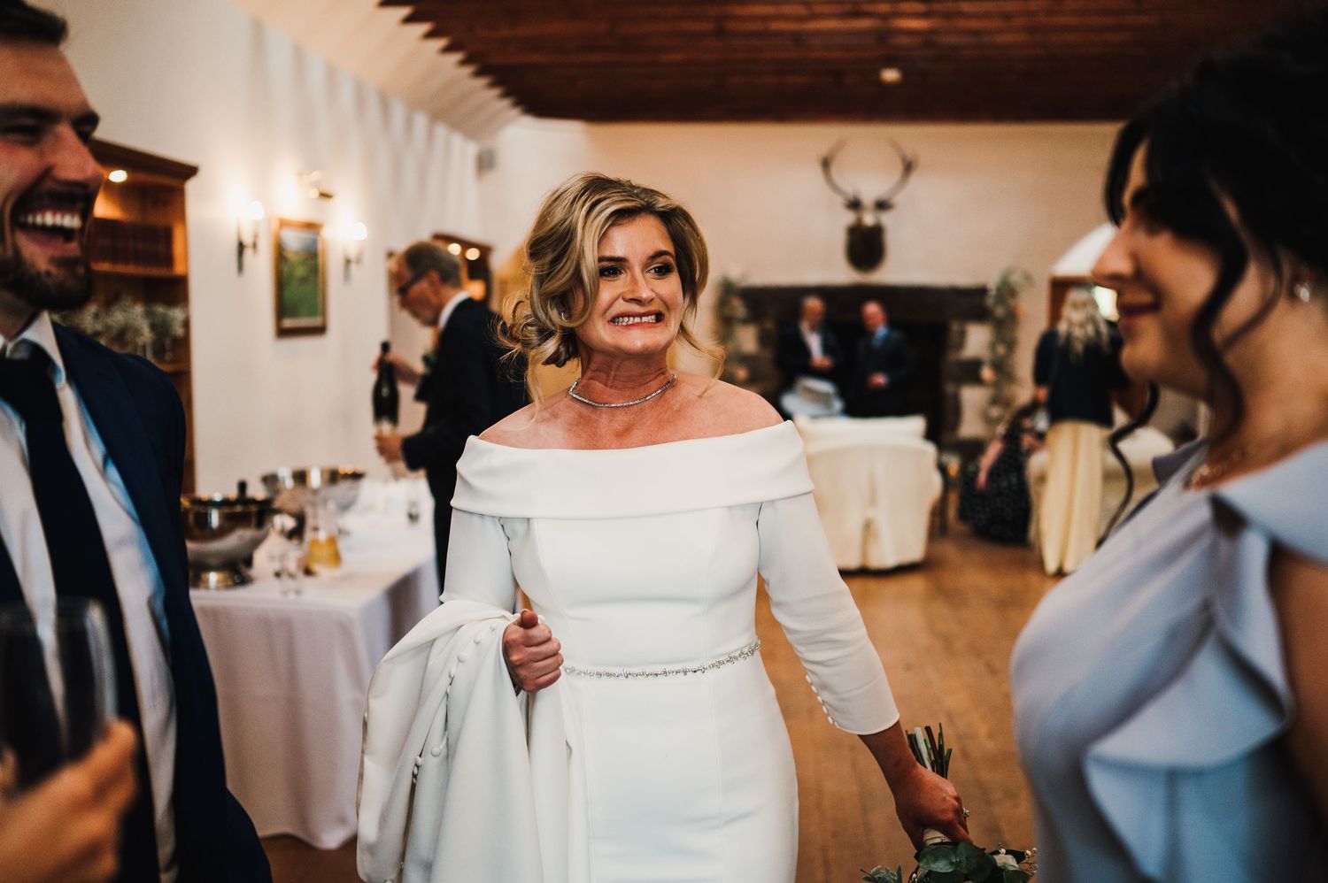 Wedding celebration in a rustic venue with white chairs and exposed wooden beams.