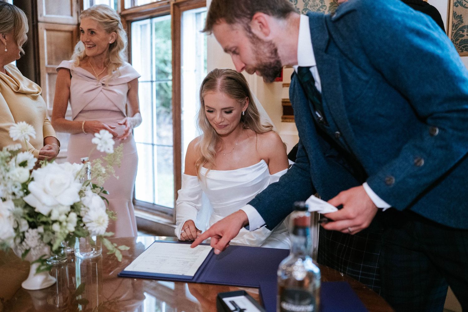 Wedding couple signing official documents during marriage ceremony.