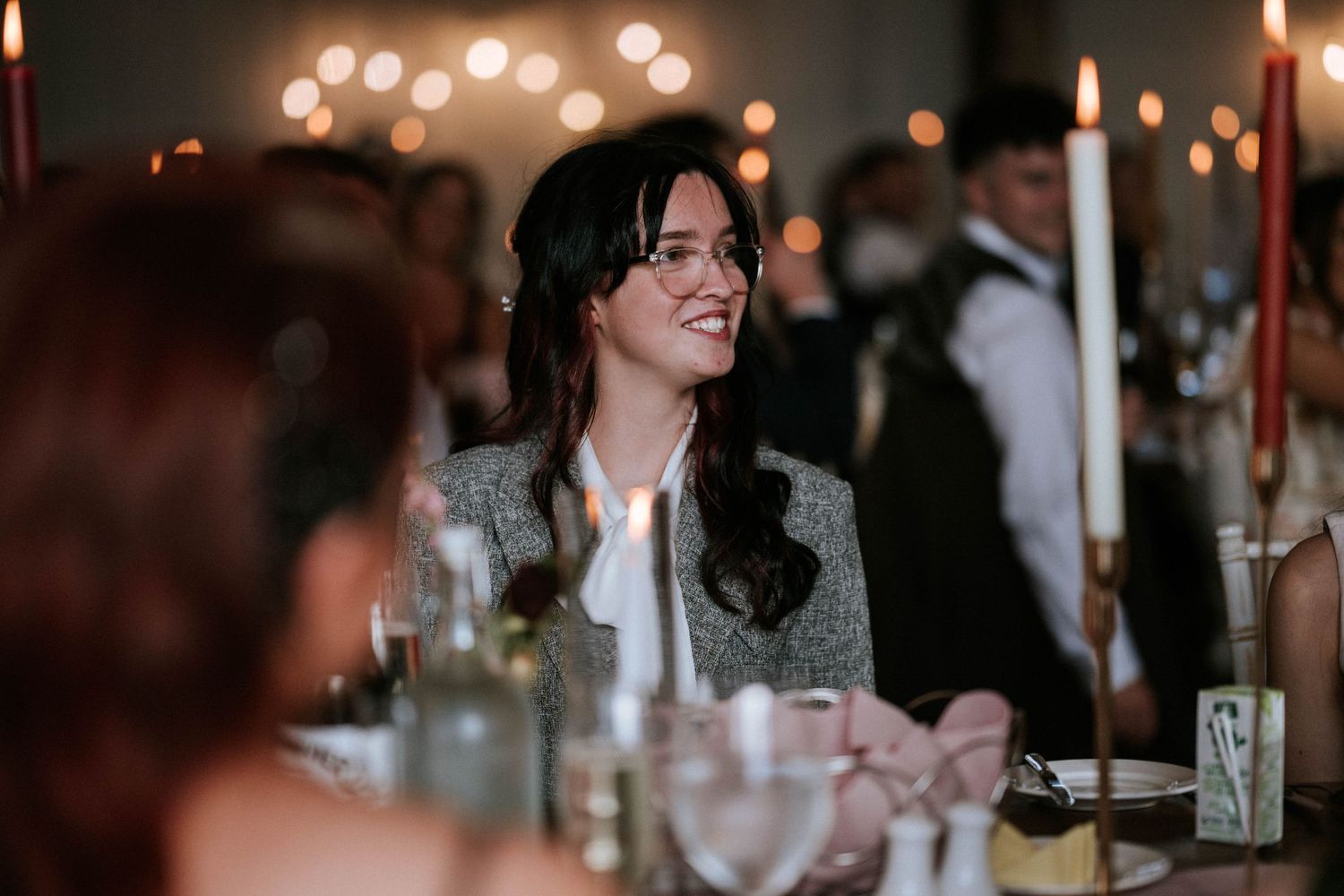 Guest enjoying conversation by candlelight at elegant wedding reception dinner.