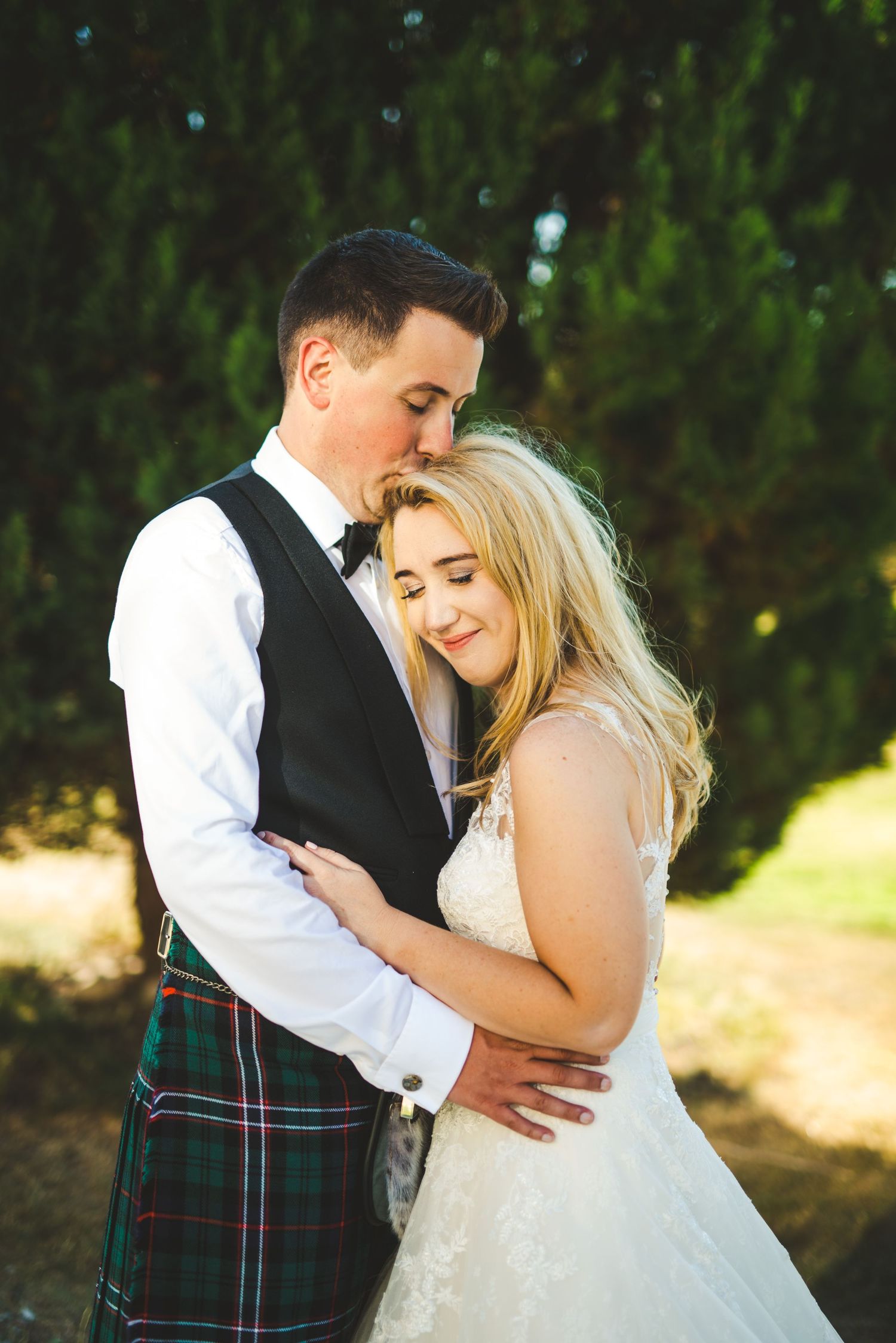 Romantic outdoor wedding portraits featuring Scottish tartan and white lace details.