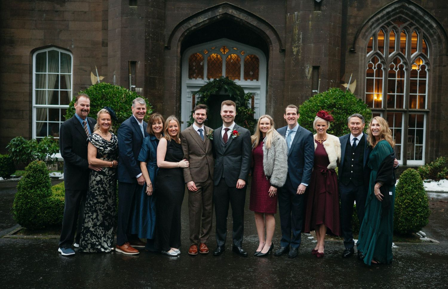 Large group gathered outside a Gothic-style brick building with arched windows and doorways.