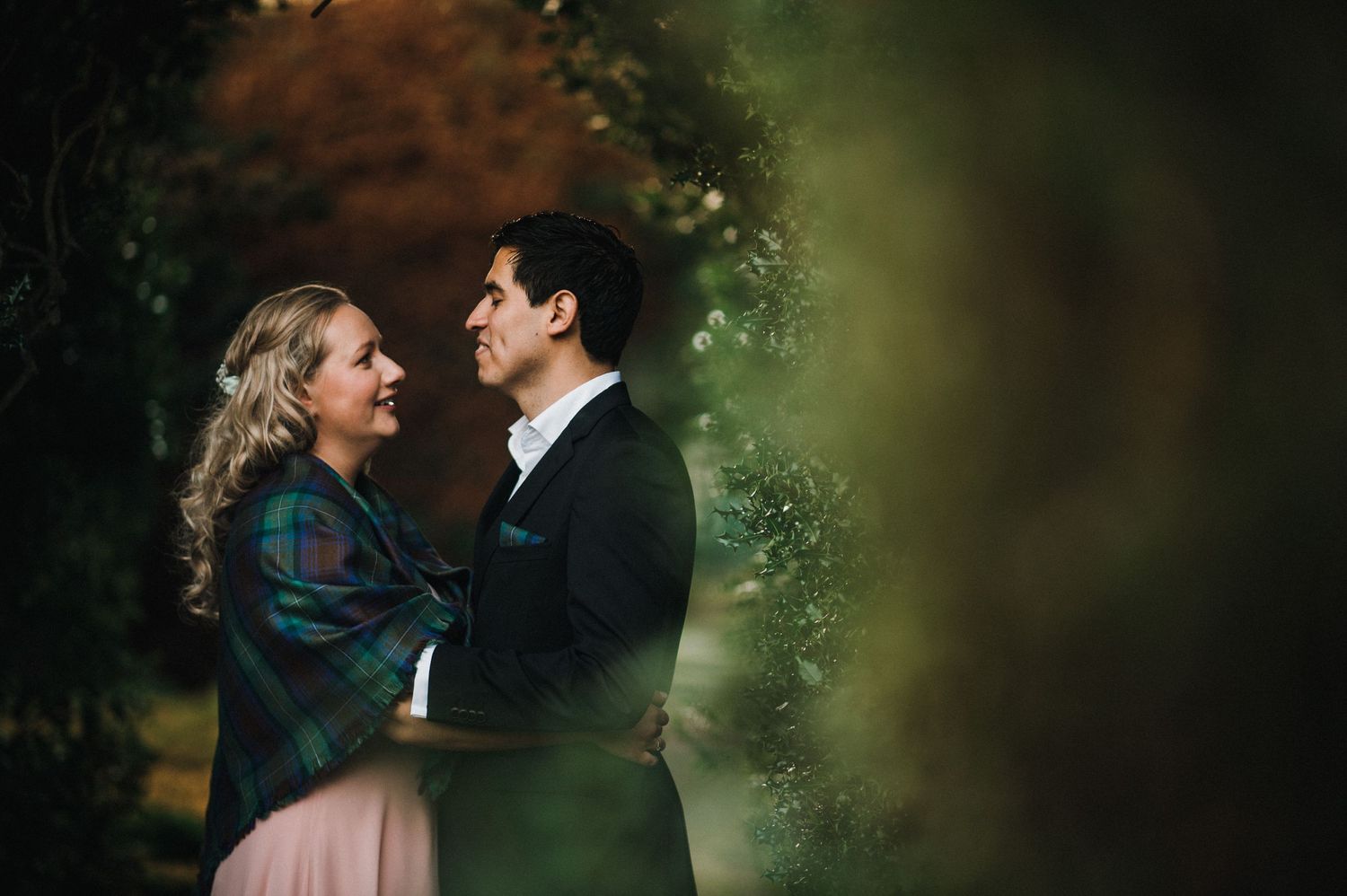 An intimate moment between a couple dressed formally against a blurred natural background.