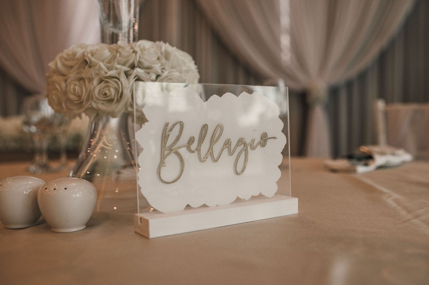 Wedding table setting with 'Bellenza' sign and white rose centerpiece.