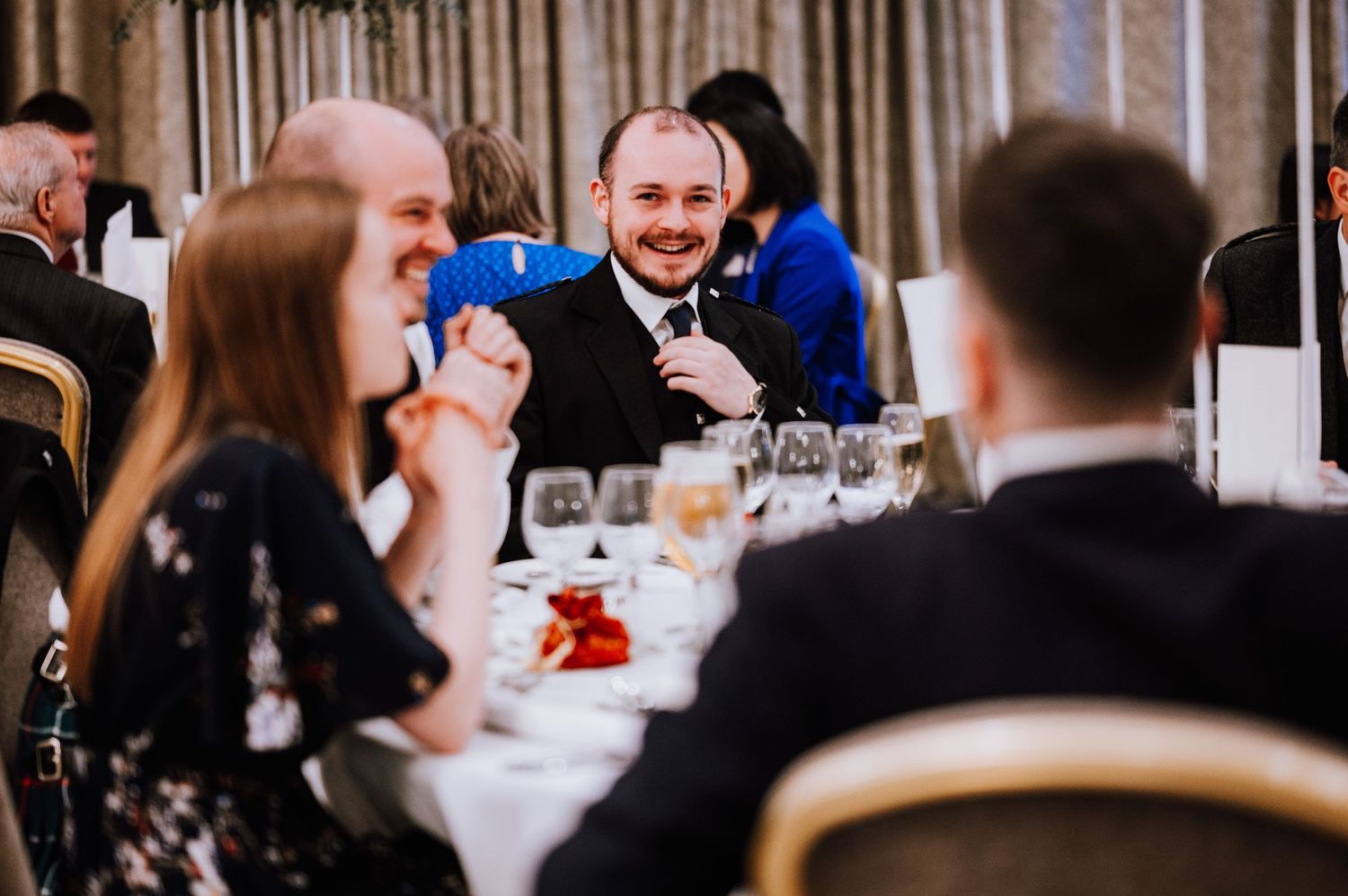 Guests sharing laughter around a formal dining table at an indoor reception.