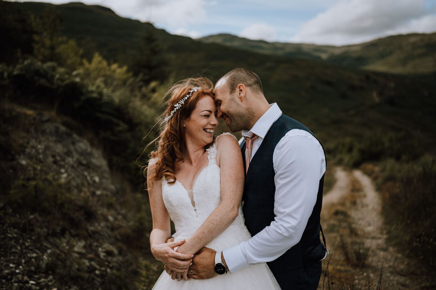 A tender moment shared between a couple on a hilltop with mountain views.
