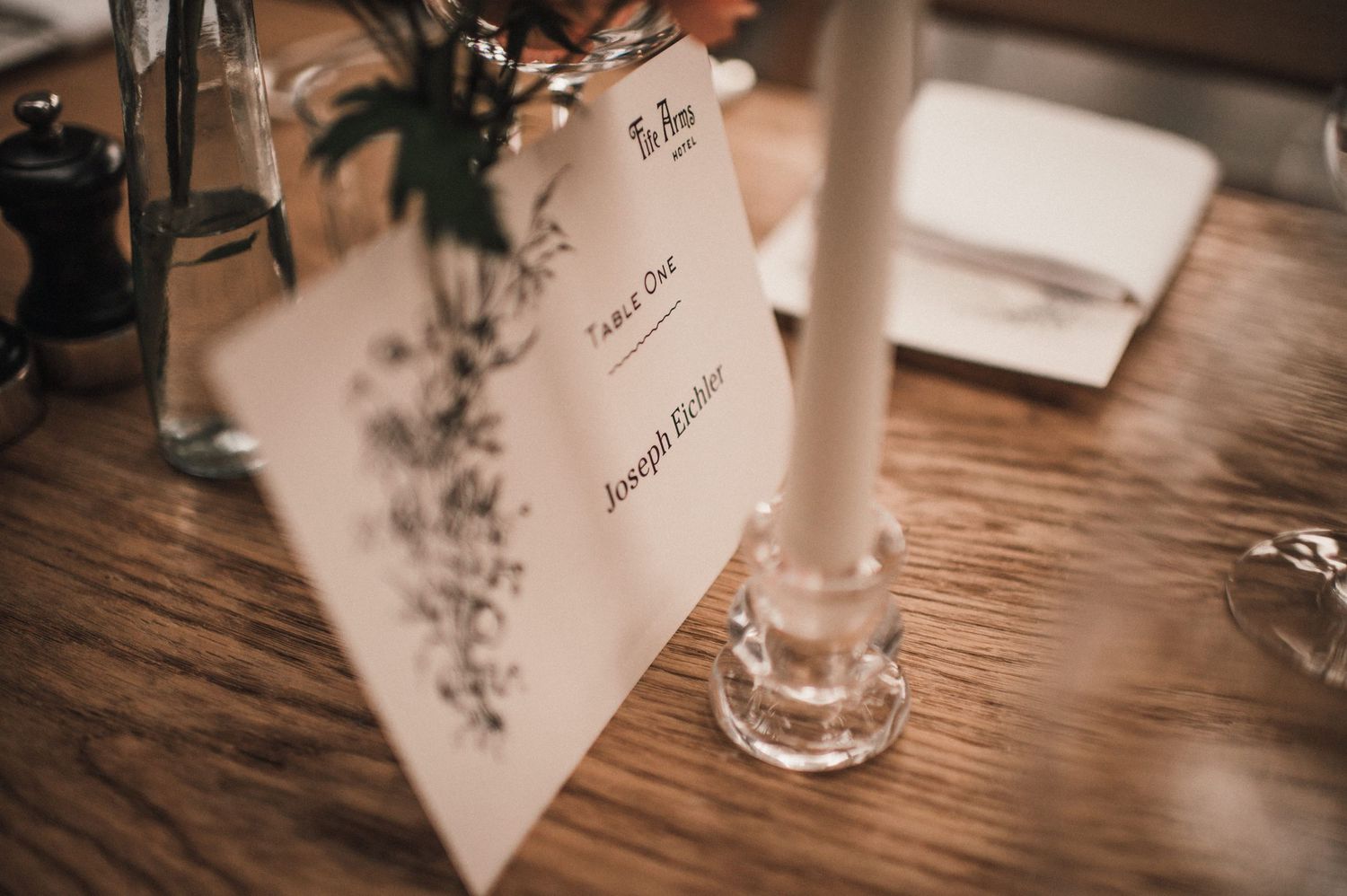 Wedding menu card and table setting with candlestick on rustic wooden table.