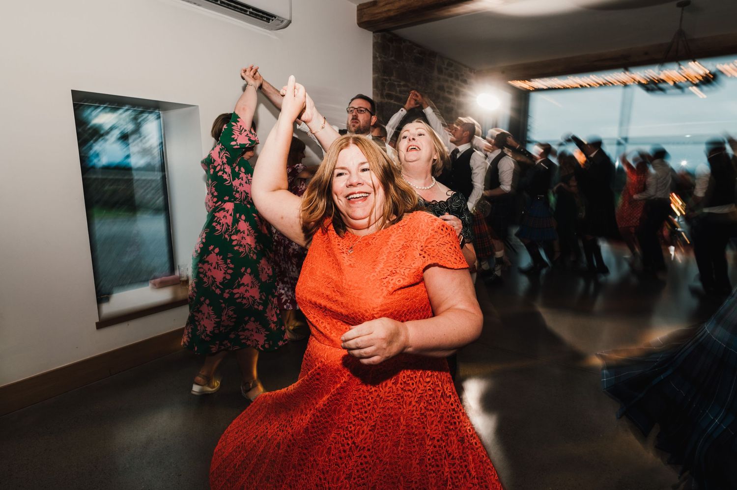 Party guests dancing enthusiastically in formal attire at an indoor celebration.