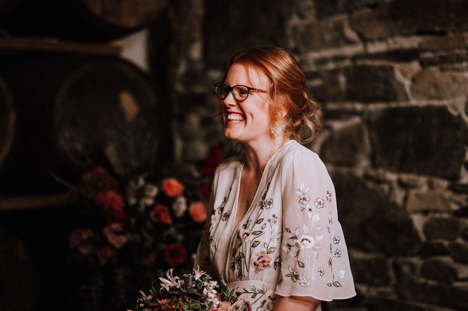 Wedding celebration in a romantic stone-walled wine cellar with floral decorations.