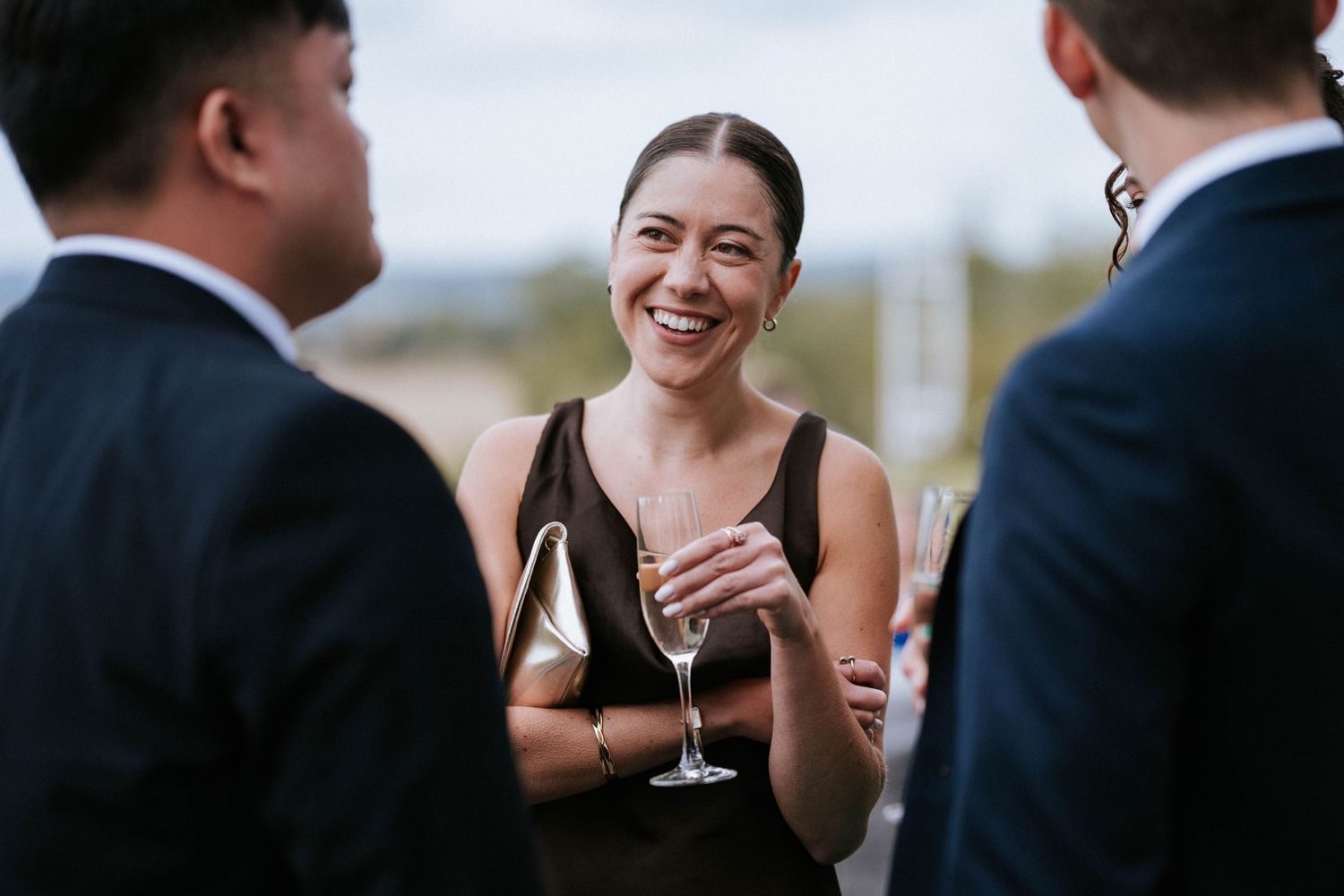 Guest enjoying champagne and conversation during elegant outdoor wedding reception.