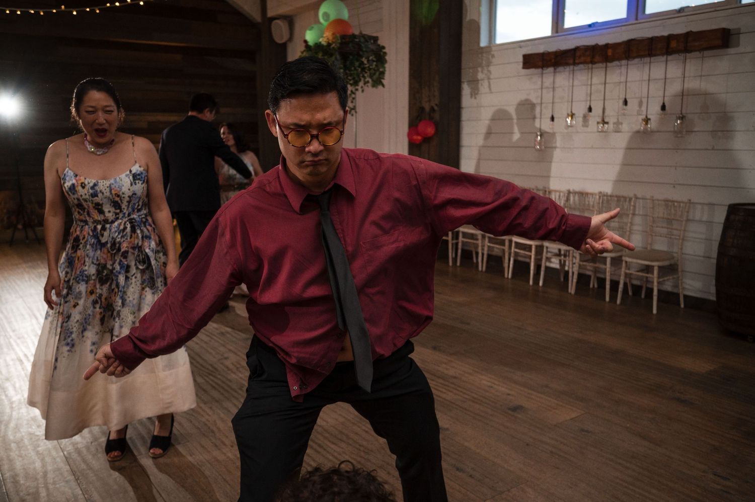 Wedding reception dance party with string lights and guests dancing.