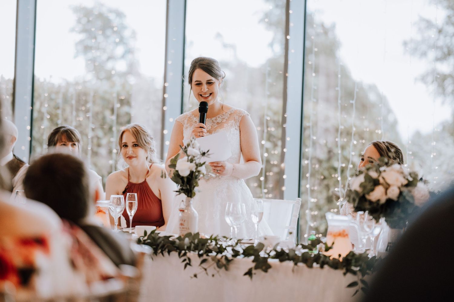 Wedding reception table decorated with floral centerpieces and glowing candles in a bright sunlit room. Meldrum House Wedding Photography.