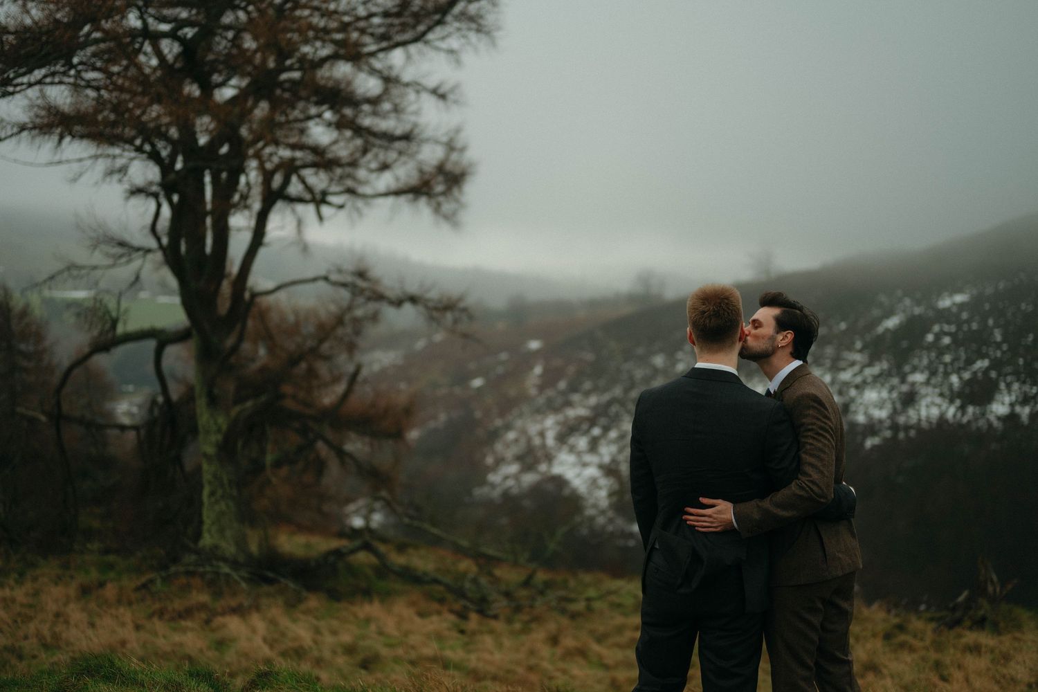 Romantic outdoor photoshoot in moody overcast weather with dramatic mountain landscape in the background.