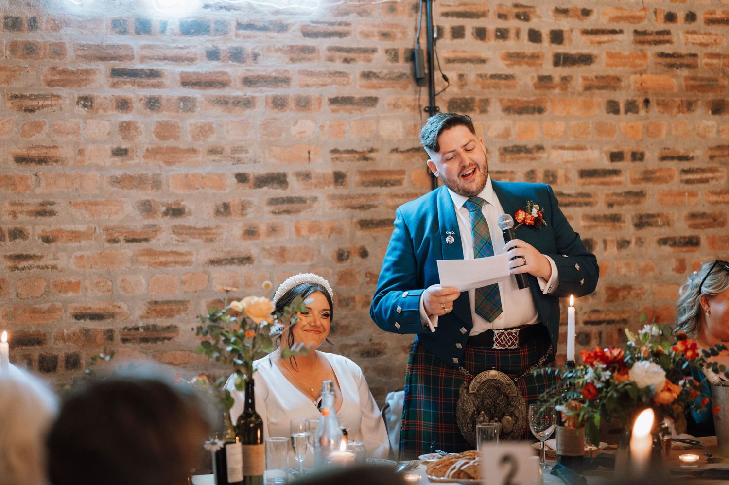 Wedding speech delivered at rustic reception venue with exposed brick walls and candlelight.