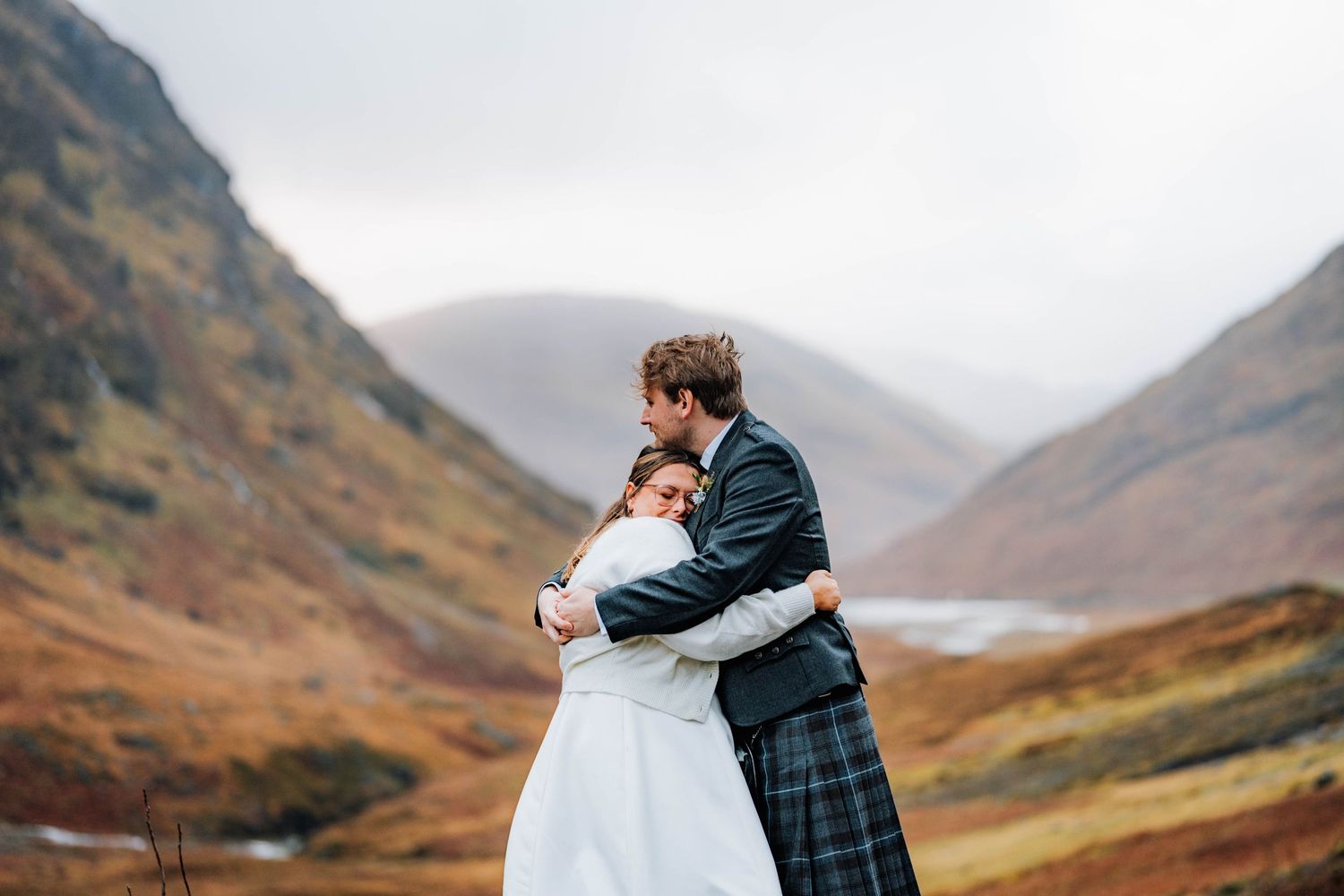A romantic wedding portrait captured against the dramatic backdrop of misty mountains and rolling hills.