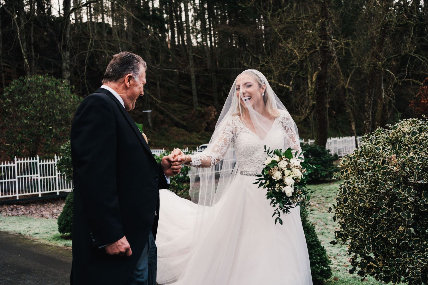 A heartfelt moment between two people during an outdoor wedding ceremony with a white picket fence backdrop.