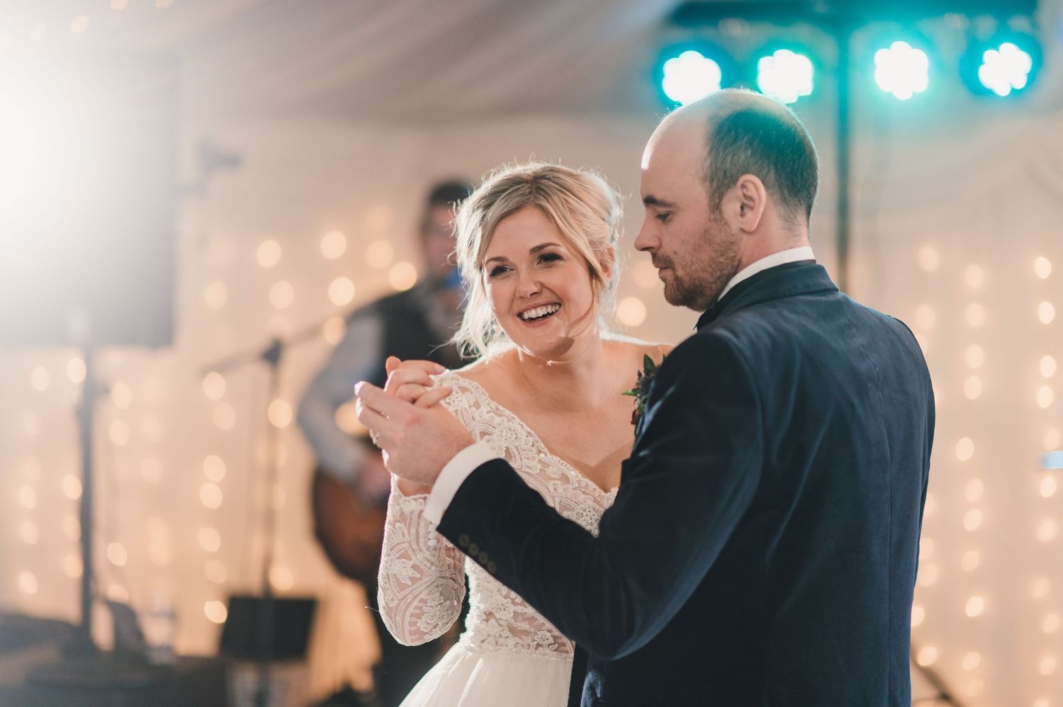 A romantic first dance moment captured under twinkling lights at a wedding reception.