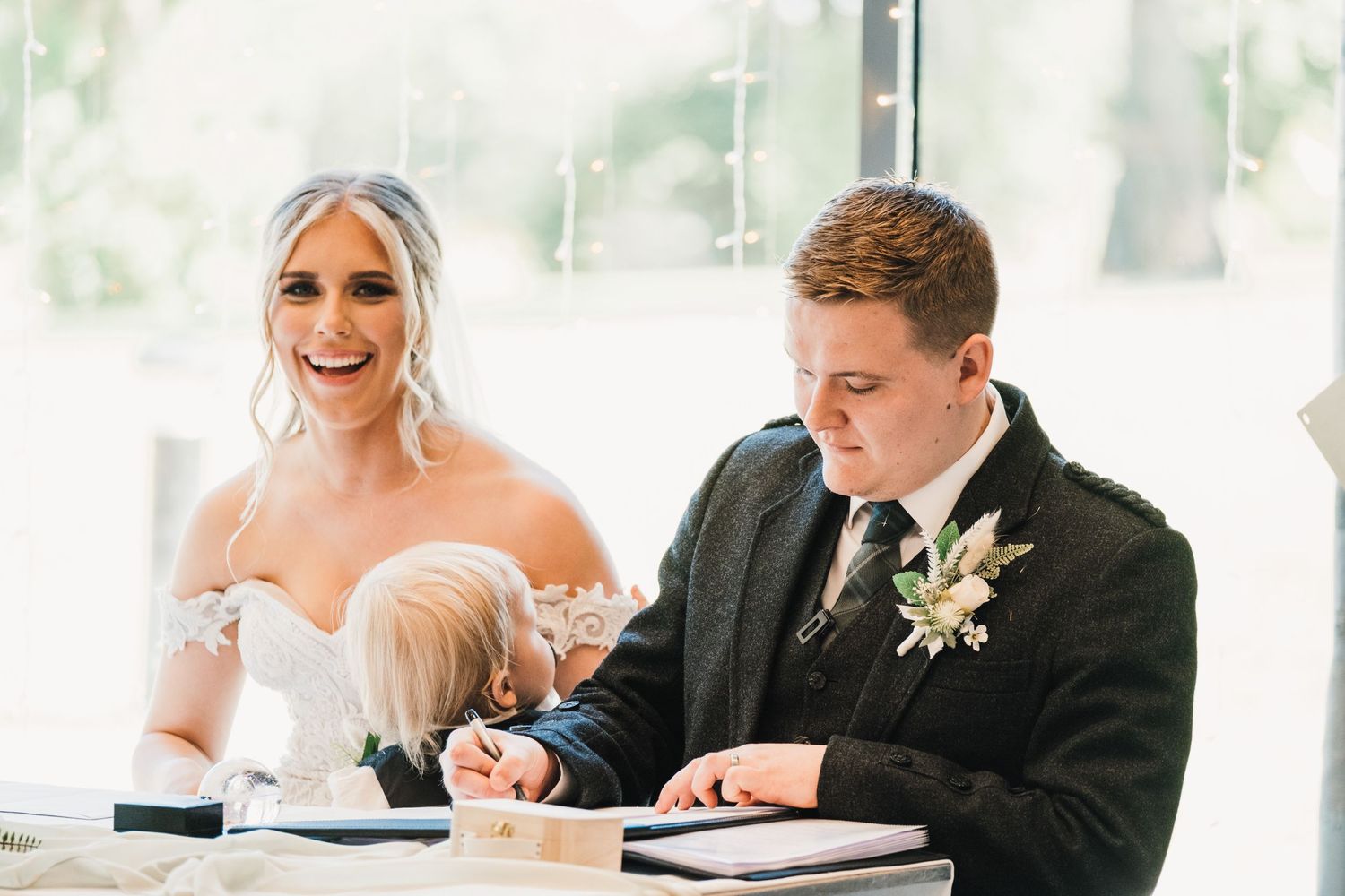 A formal document signing at a wedding with traditional Scottish and modern formal attire.