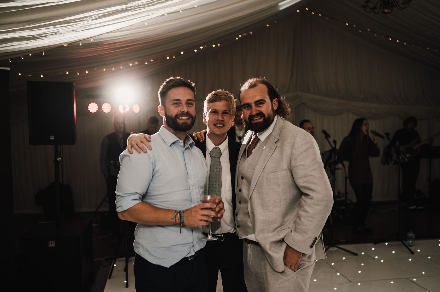 Three guests posing together for a photo during an indoor wedding reception.