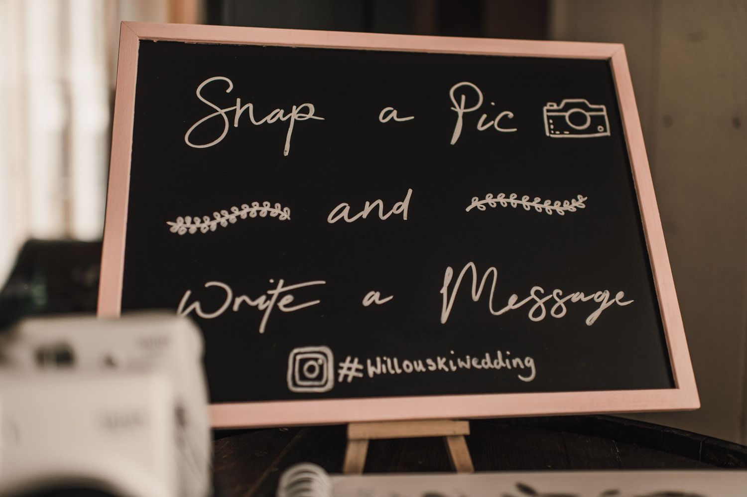 Chalkboard sign at wedding encouraging guests to take photos and write messages.