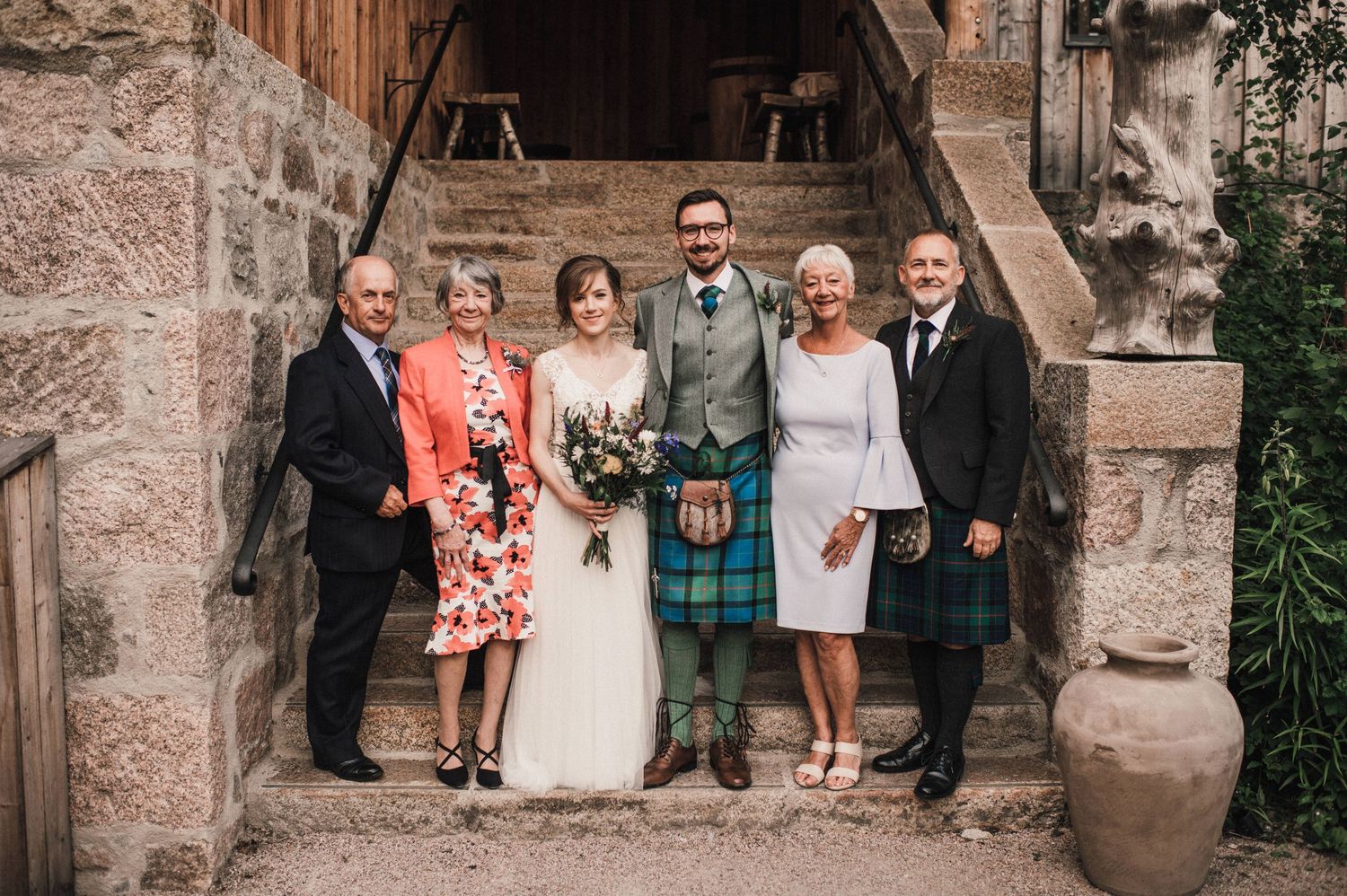 Family wedding portrait on stone steps with Scottish traditional dress and formal attire.