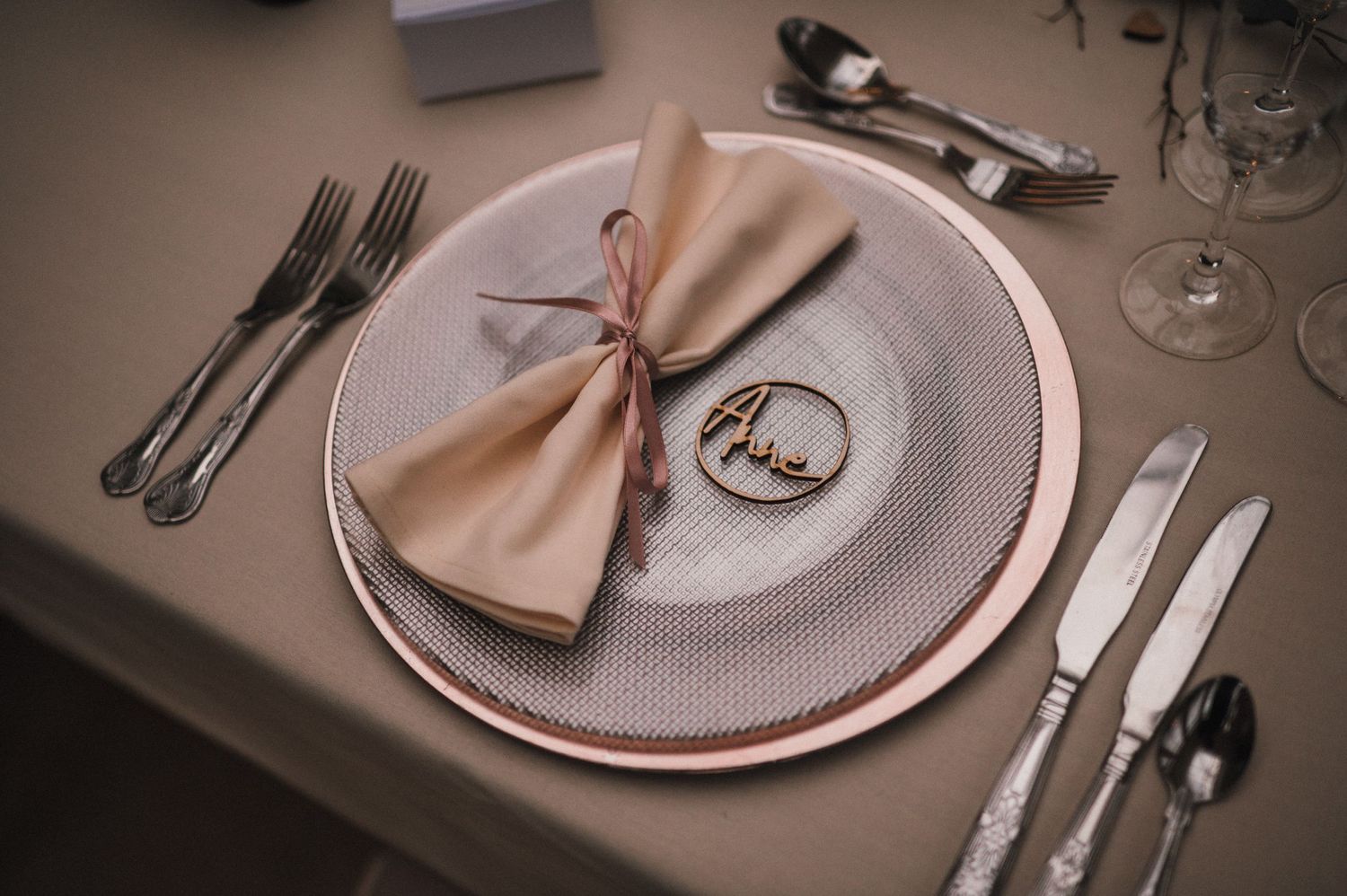 Elegant place setting with rose gold napkin and plate at a wedding reception.
