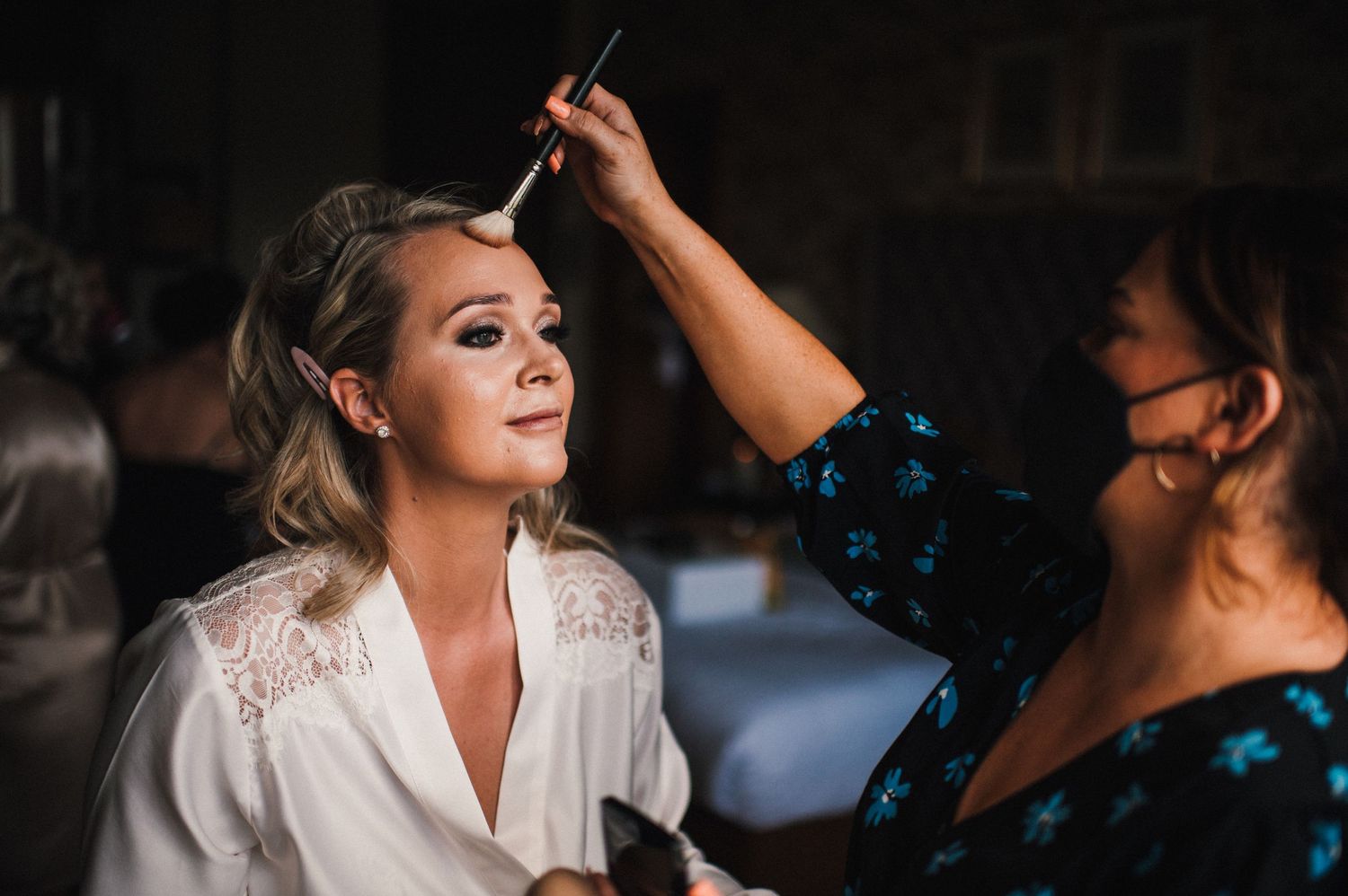 Makeup artist applies finishing touches during bridal preparation.