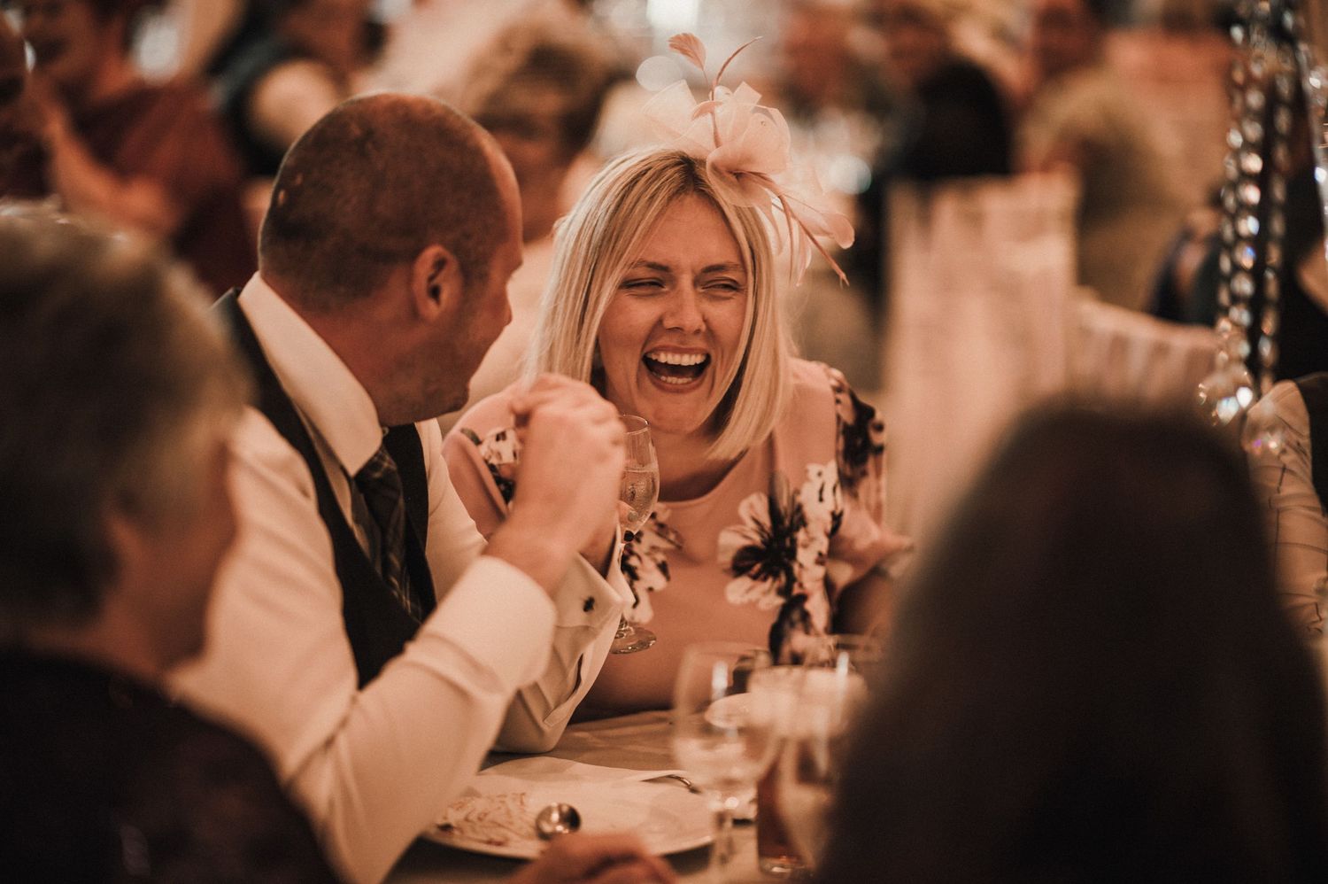 Candid moment of joyful laughter during a wedding reception dinner celebration.