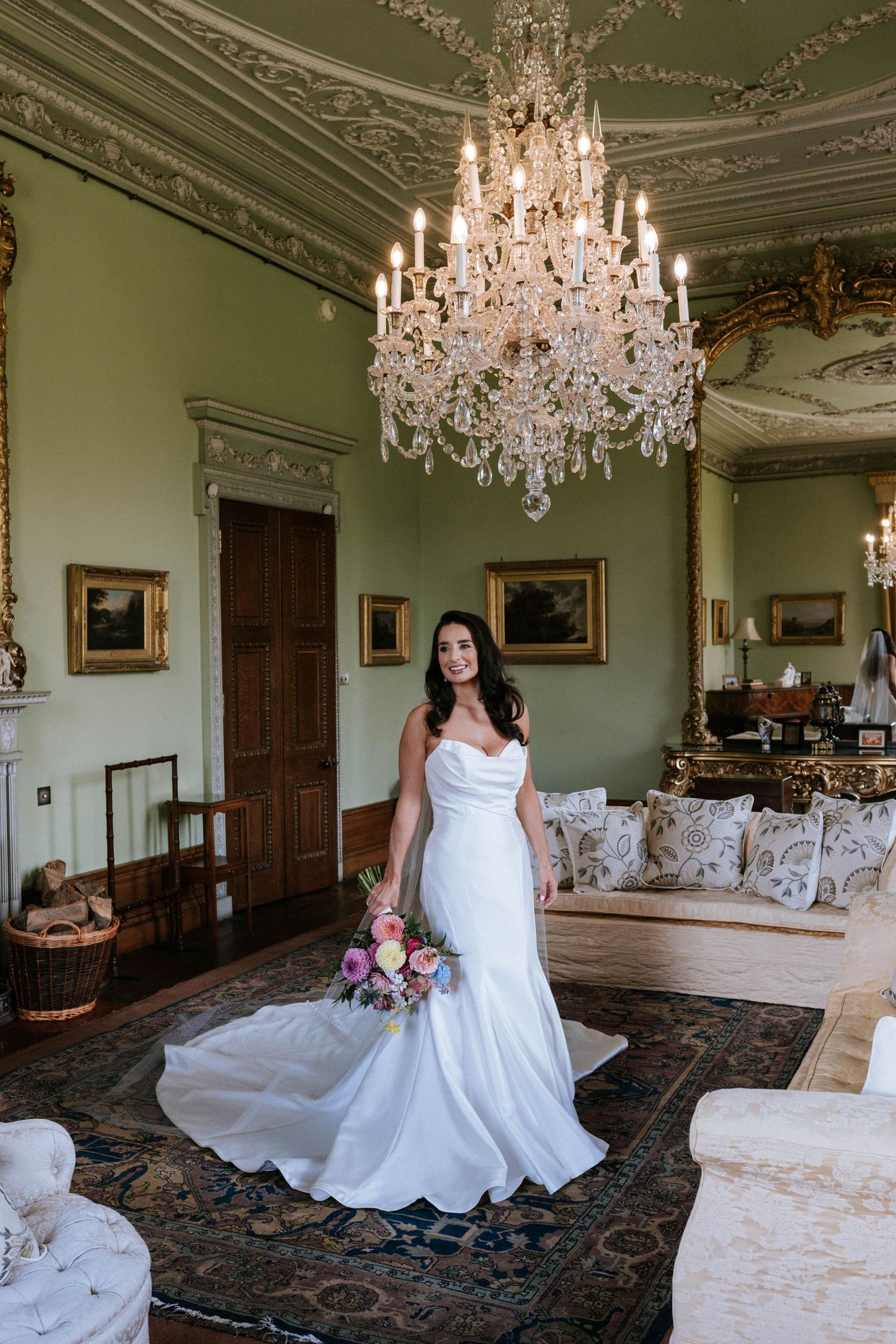 Elegant room with crystal chandelier and ornate moldings featuring a white wedding dress.