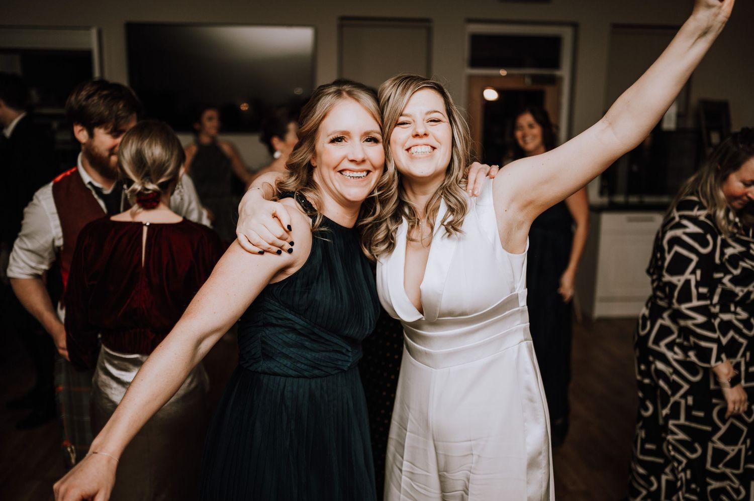Same Sex Wedding Photography. Wedding party dancing and celebrating in a dark reception space.
