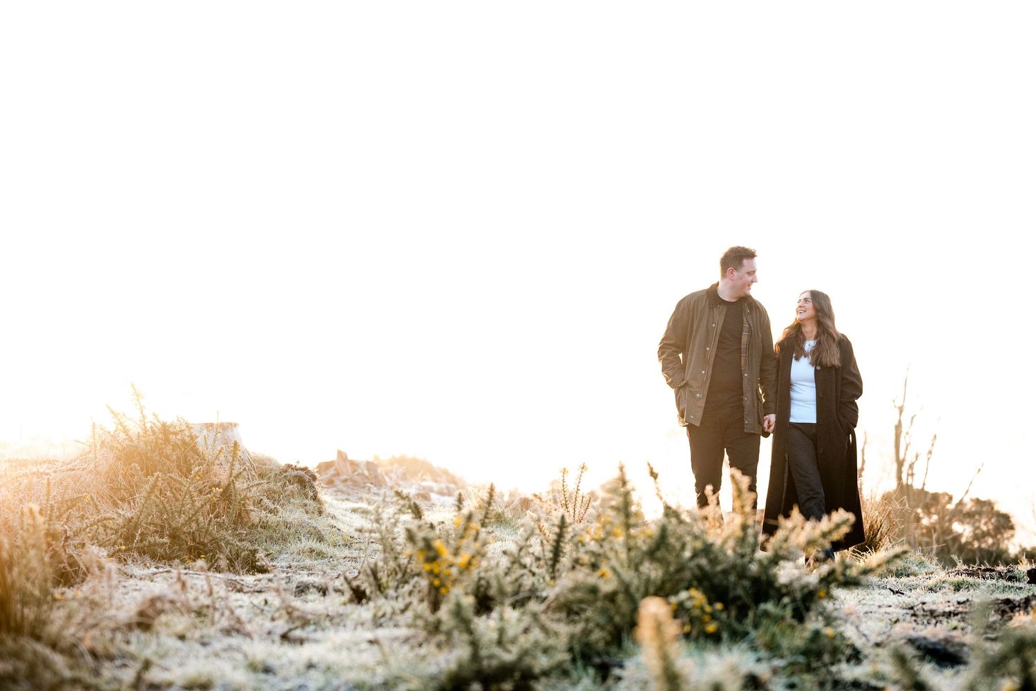Engagement photography session Aberdeen. A couple stands in silhouette against a bright winter landscape.