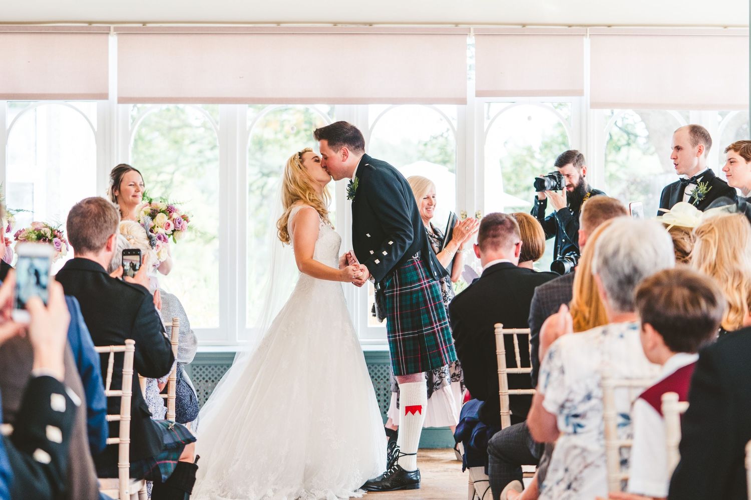 Wedding reception guests dancing and celebrating in an elegant white tent venue.