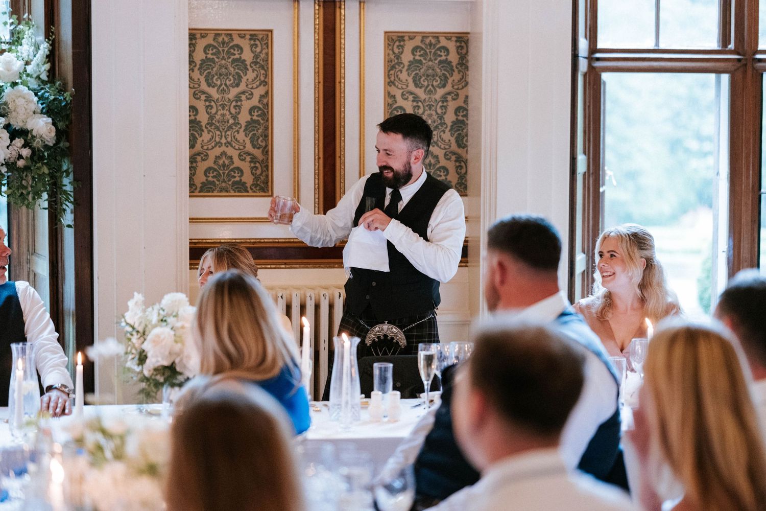 Wedding reception venue with elegant decor and large windows overlooking natural scenery.